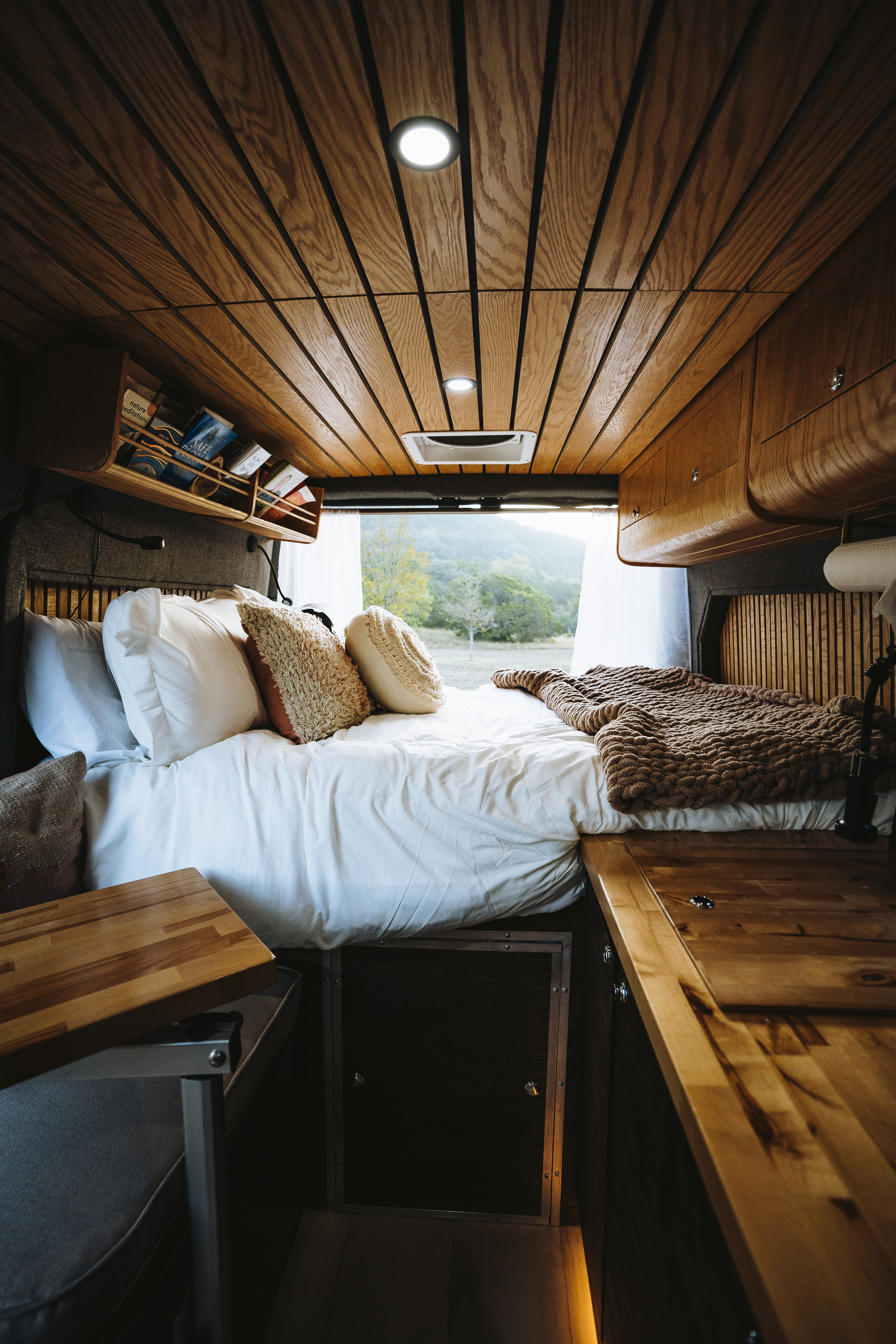 Cozy RV rental interior with a comfy bed, wood ceiling, and stunning nature views. Perfect for adventure!. Dodge 1500 2020