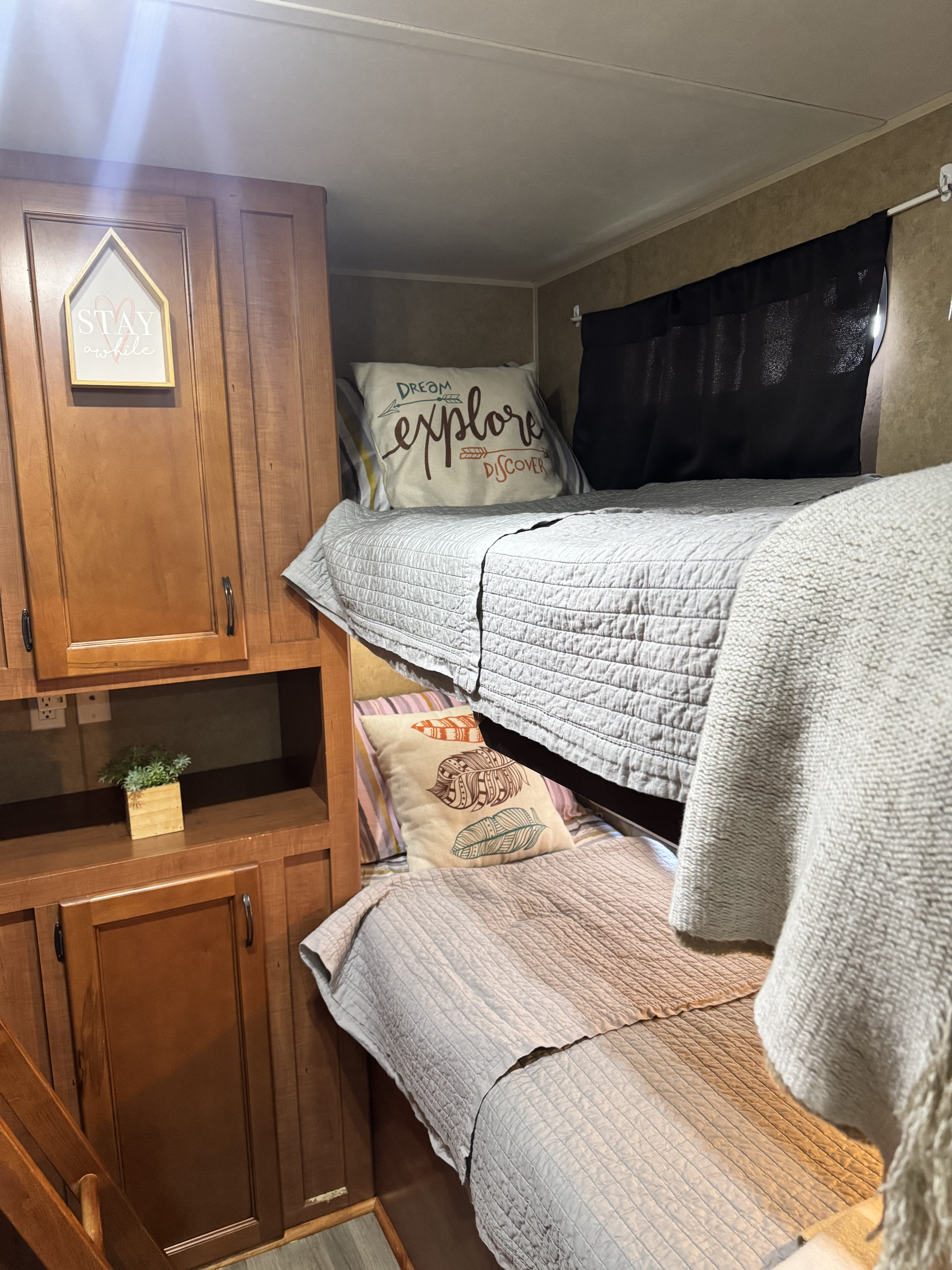 RV rental interior featuring cozy bunk beds, complete with bedding and decorative pillows, alongside functional wooden cabinetry.. Forest River Cherokee Grey Wolf 2013