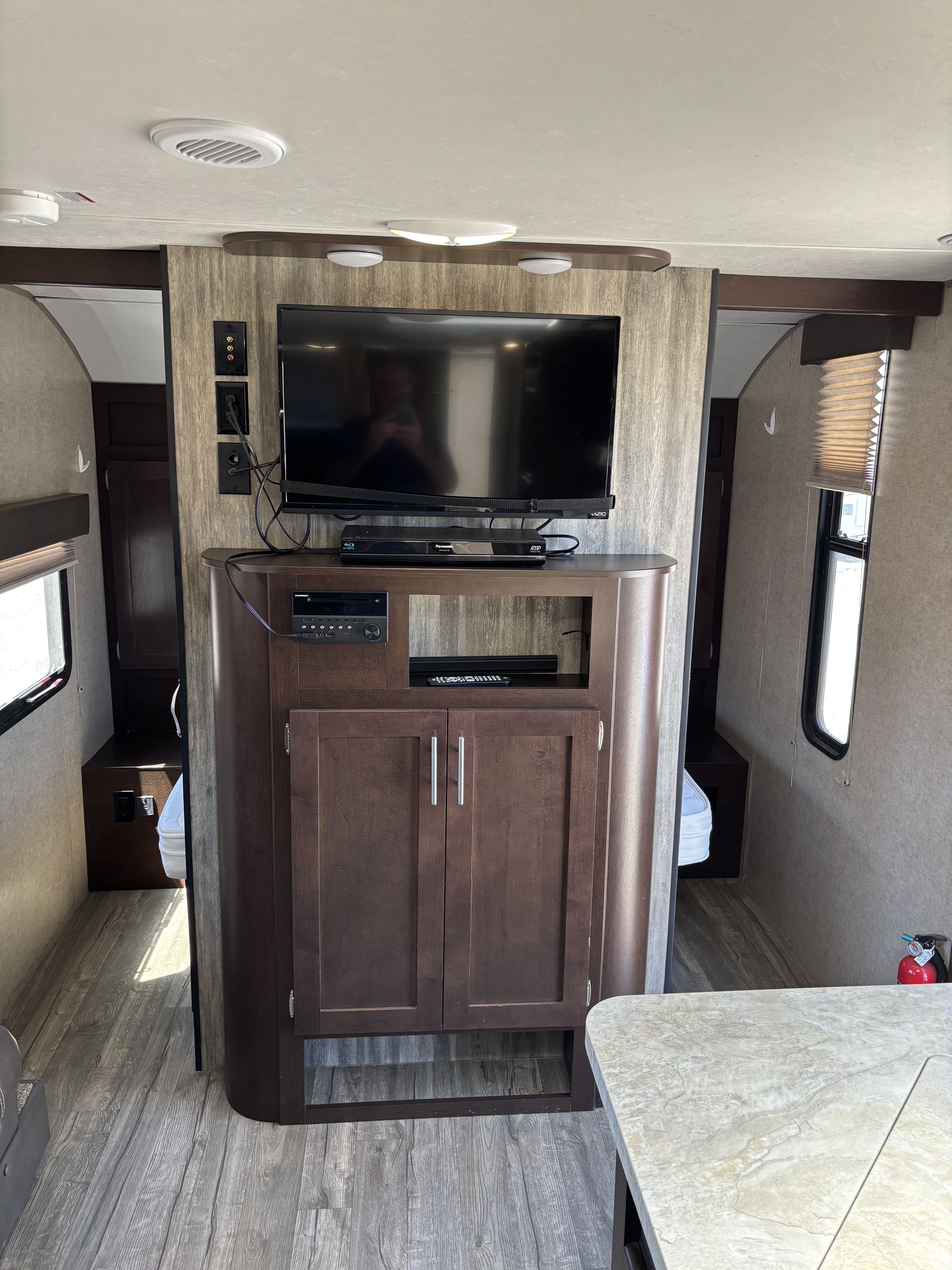 RV rental interior: Entertainment console with TV, media setup, dark wood cabinetry, and light wood-look flooring.. Forest River Cherokee 2017