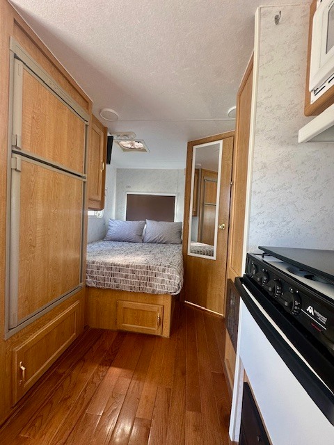 RV rental interior: View of a compact mobile living space with a bed, kitchen appliances, and wood floors.. Nomad Lite 2000