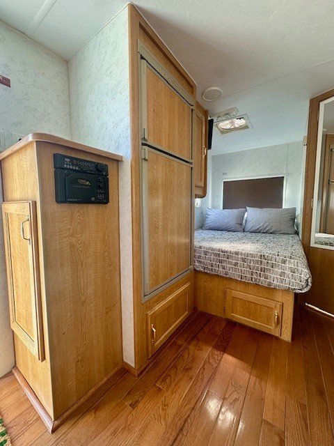 RV rental interior: bedroom, built-in refrigerator, and stereo cabinet with wood finishes and hardwood floors.. Nomad Lite 2000