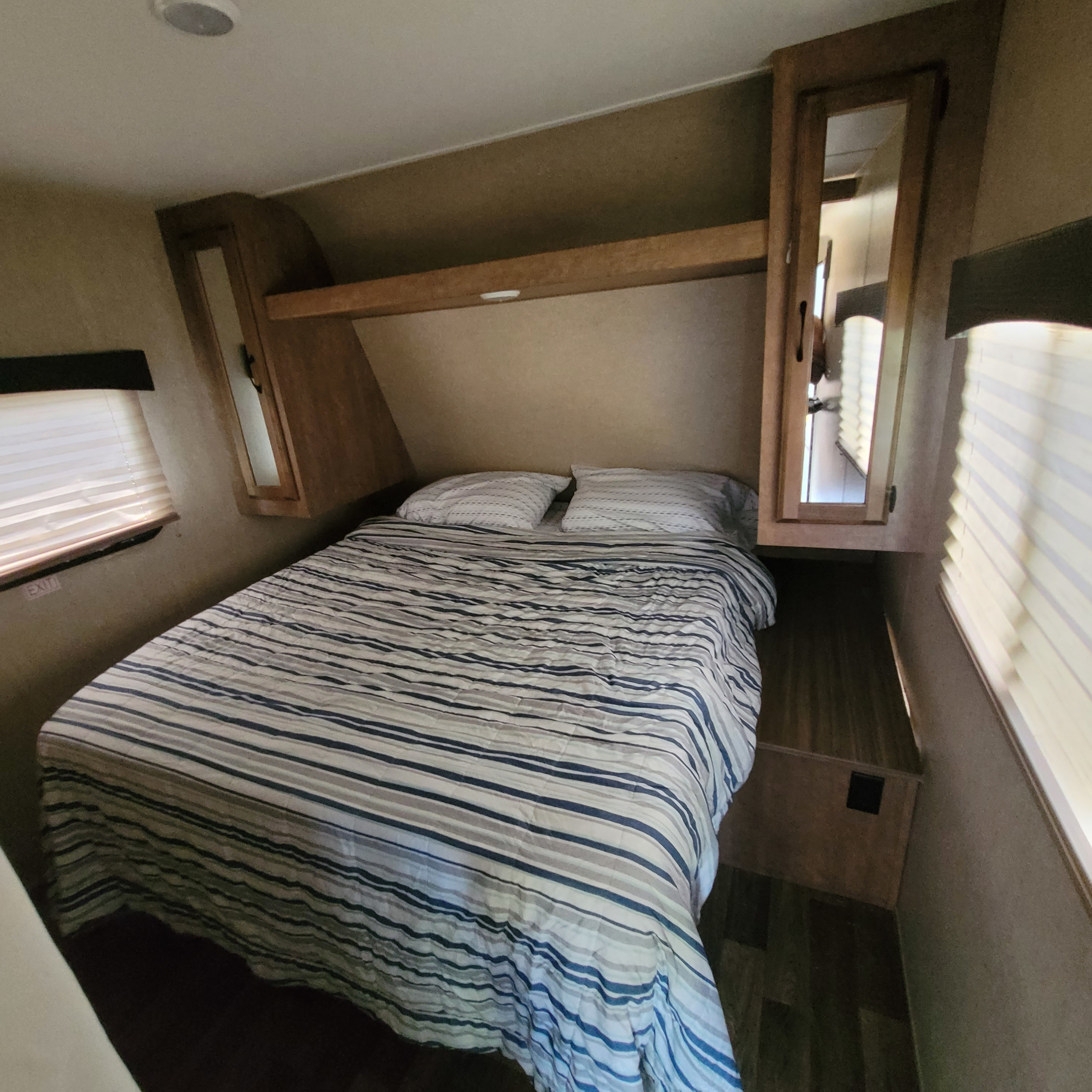 Comfortable RV rental bedroom featuring a bed with striped covers, mirrored cabinets, and window blinds.. Starcraft Launch Ultra Lite 2018
