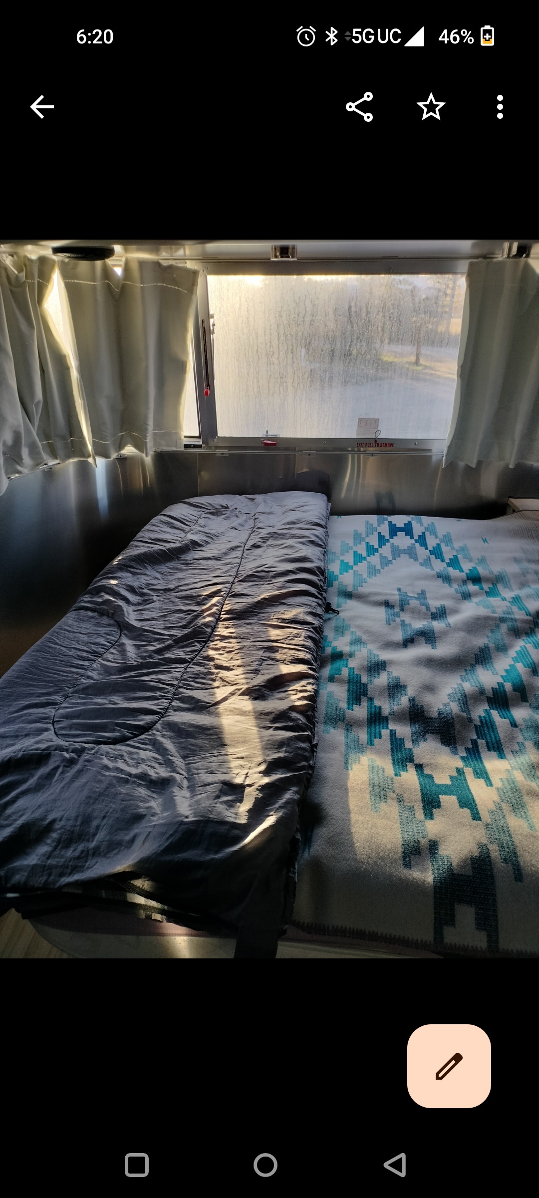 Cozy RV rental interior: Two beds with a patterned blanket, bathed in natural light from a scenic window view.. Airstream International 2019