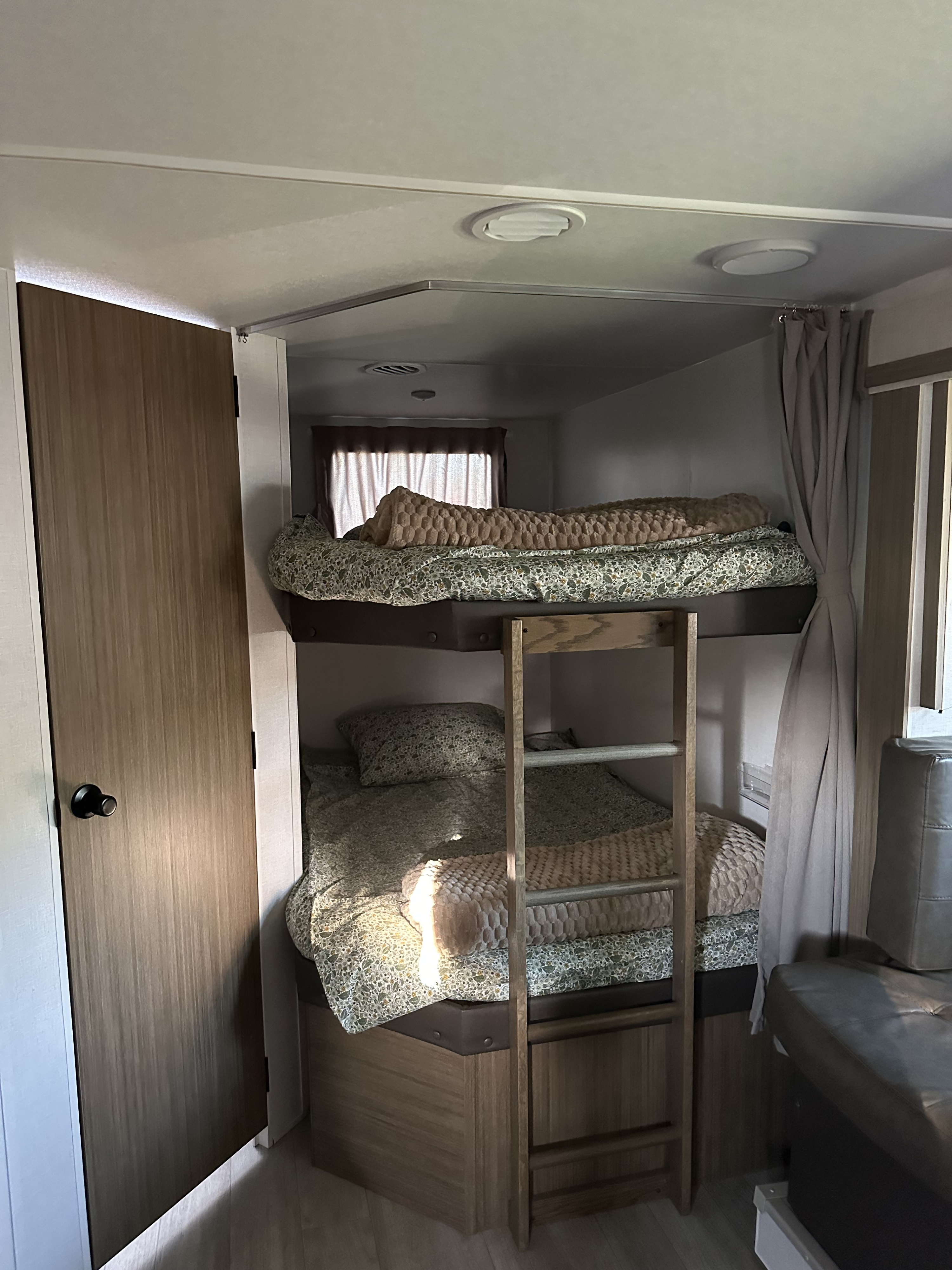 RV rental's cozy bunk bed setup, complete with patterned bedding, a wooden ladder, and a privacy curtain.. Forest River Forest River Salem Cruise Lite 263BHXL 2025