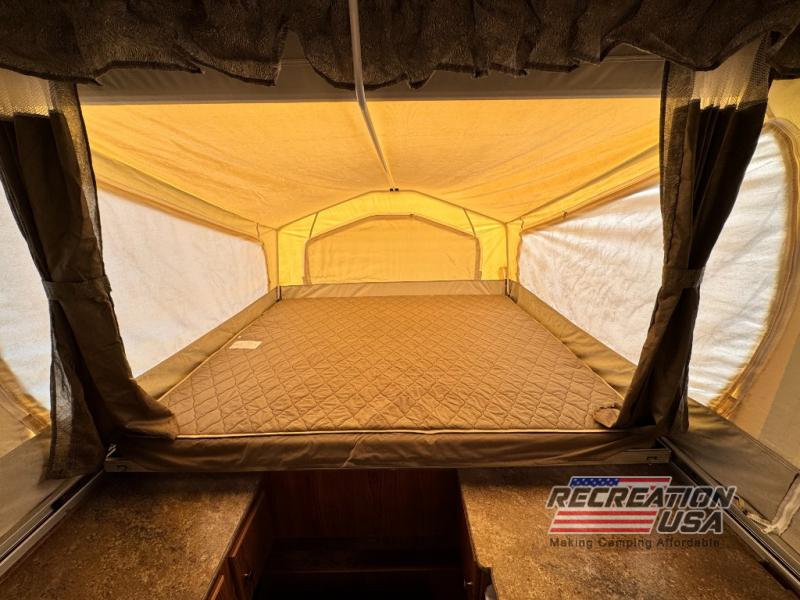 Step into a cozy RV rental: a pop-up camper's interior with a large, comfortable bed and spacious canvas walls for camping adventures.. Forest River Rockwood 2016