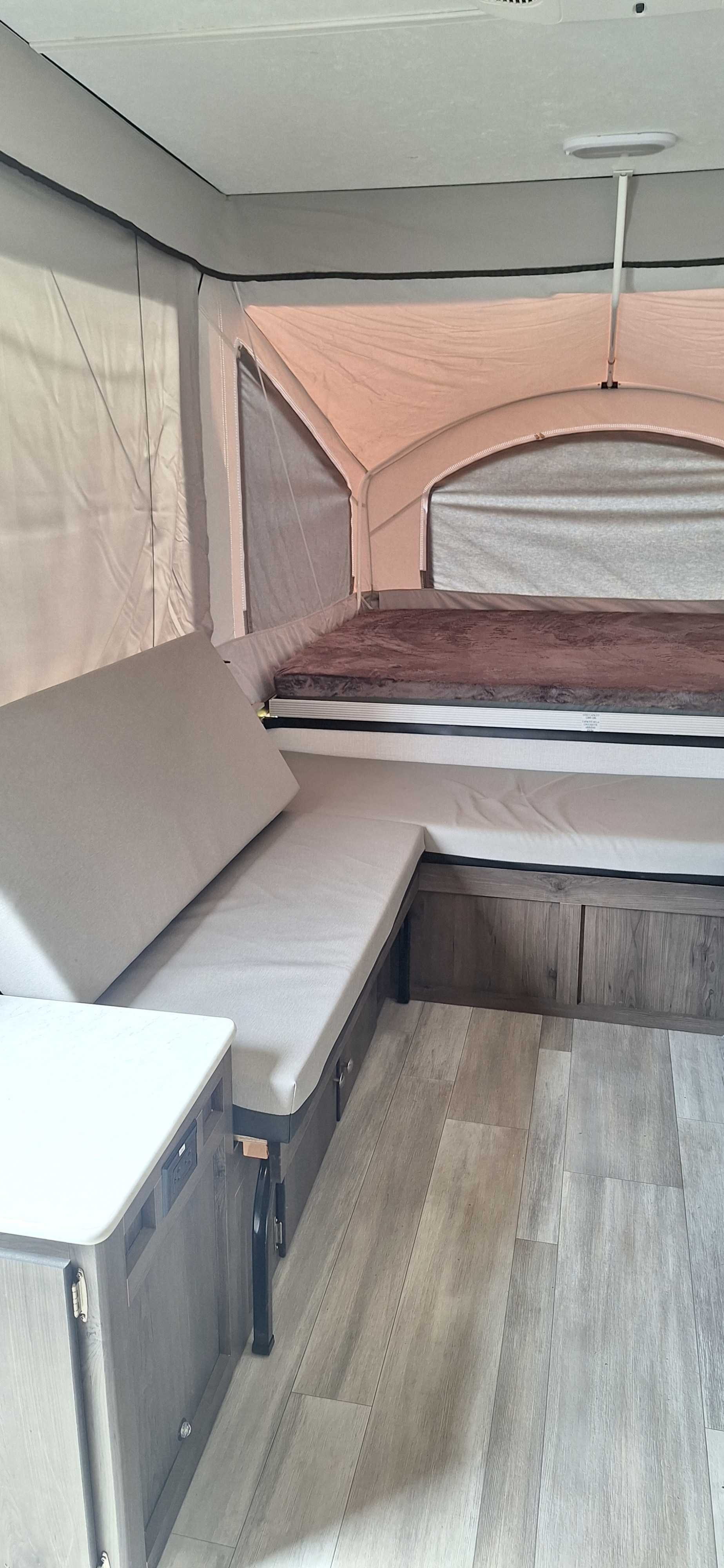 Modern RV rental pop-up camper interior: comfy bunk, convertible dinette, and wood-look floor.. Forest River Viking 2022