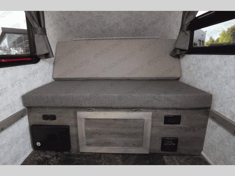 Cozy RV rental interior with grey cushioned bench, window views, and accessible outlets/storage for compact travel.. Prolite Prolite Trailer 2018