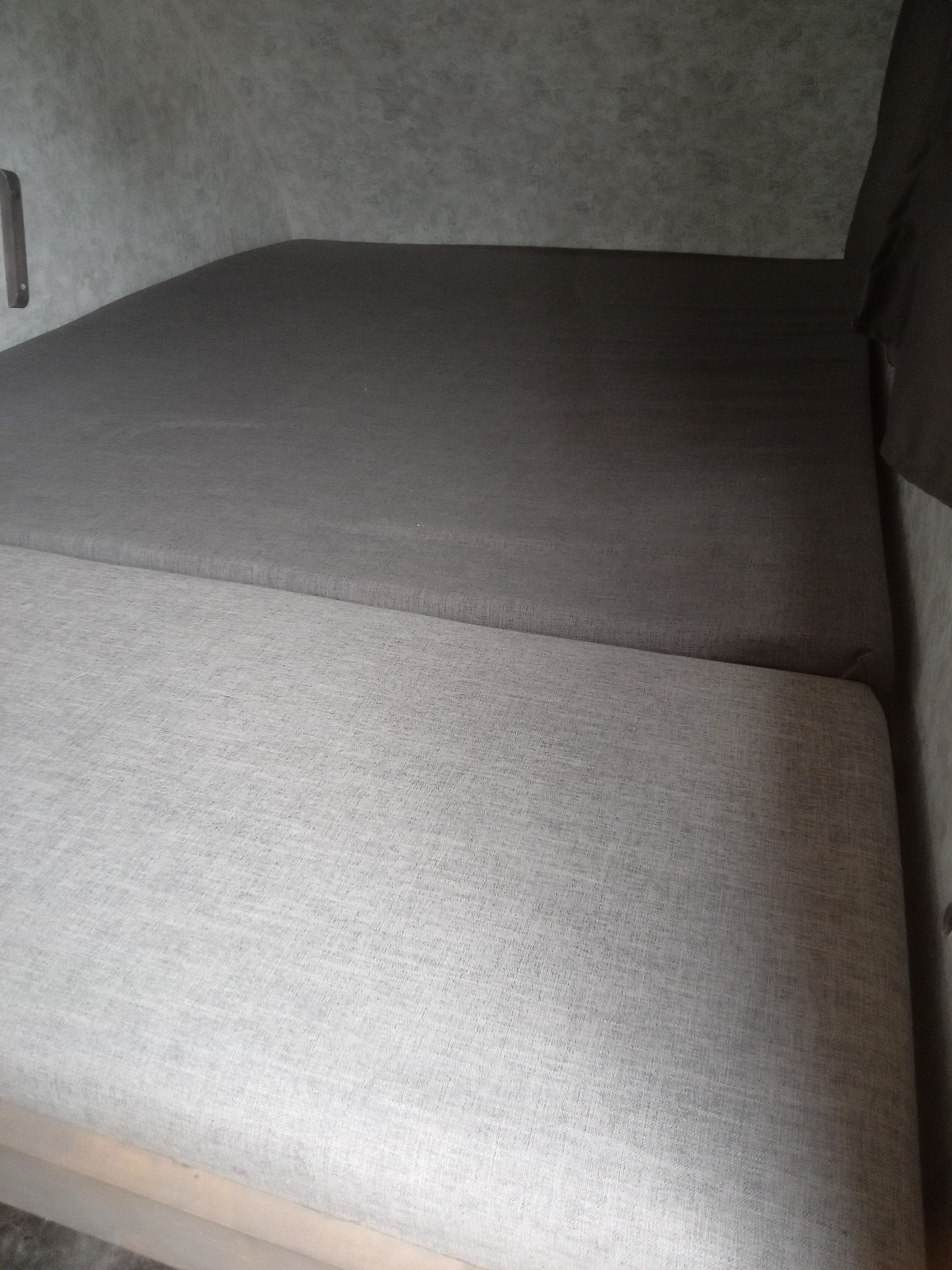 RV rental interior: Grey upholstered cushions form a comfortable bed in this compact space.. Prolite Prolite Trailer 2018
