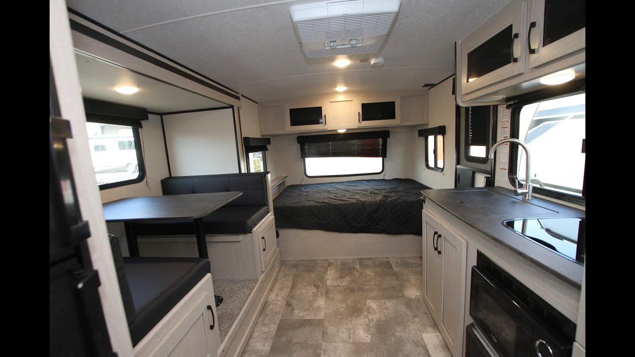Inside this **rv rental**: A modern interior featuring a dinette on the left, a bed in the back, and a functional kitchen on the right.. Coachmen Apex Nano 2021