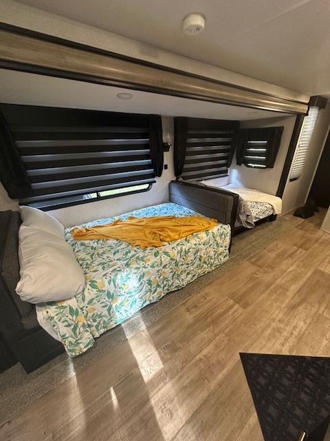 Cozy RV rental interior showing two sleeping areas with bright bedding and privacy blinds, perfect for family adventures.. Forest River Cherokee 2022