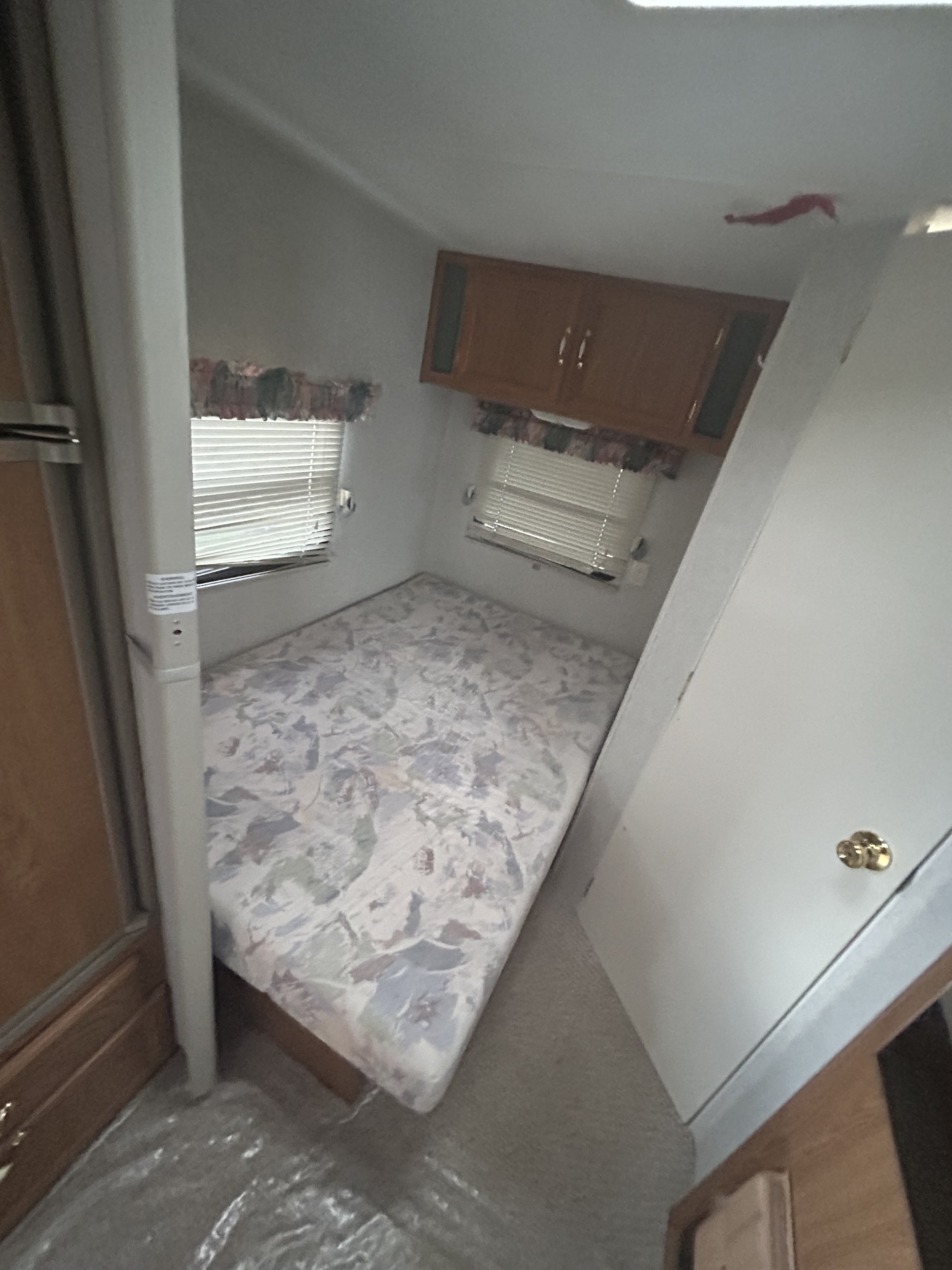 RV rental interior: cozy bedroom featuring a patterned mattress, windows, and storage cabinets.. Fleetwood Wilderness 1997
