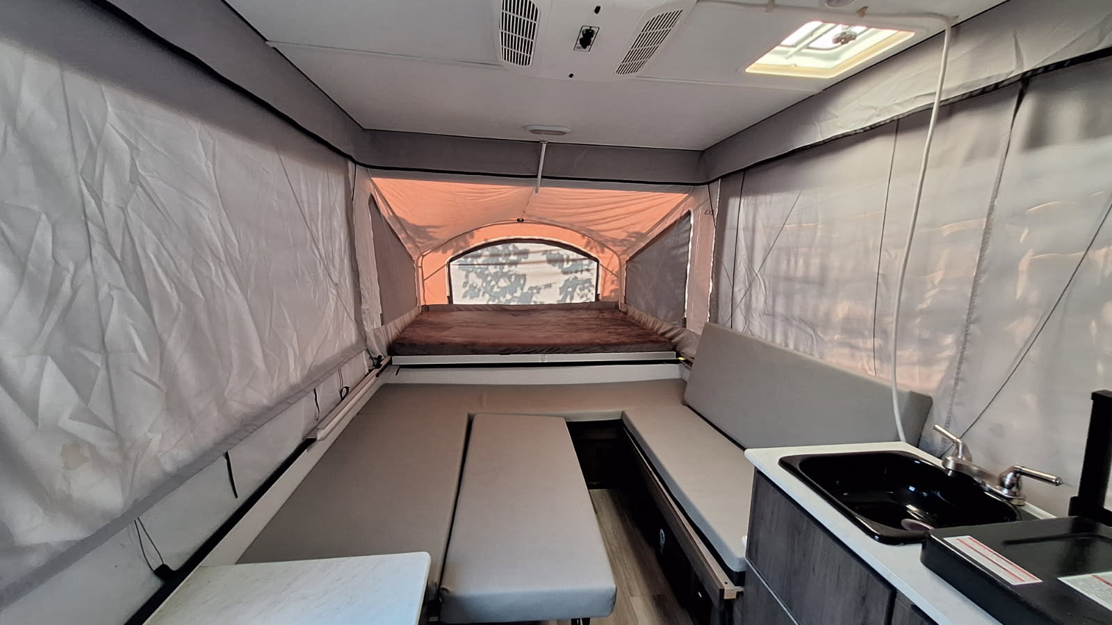 Explore this pop-up RV rental's interior: a cozy bed, convertible dinette, and functional kitchen ready for your journey.. Forest River Viking 2022