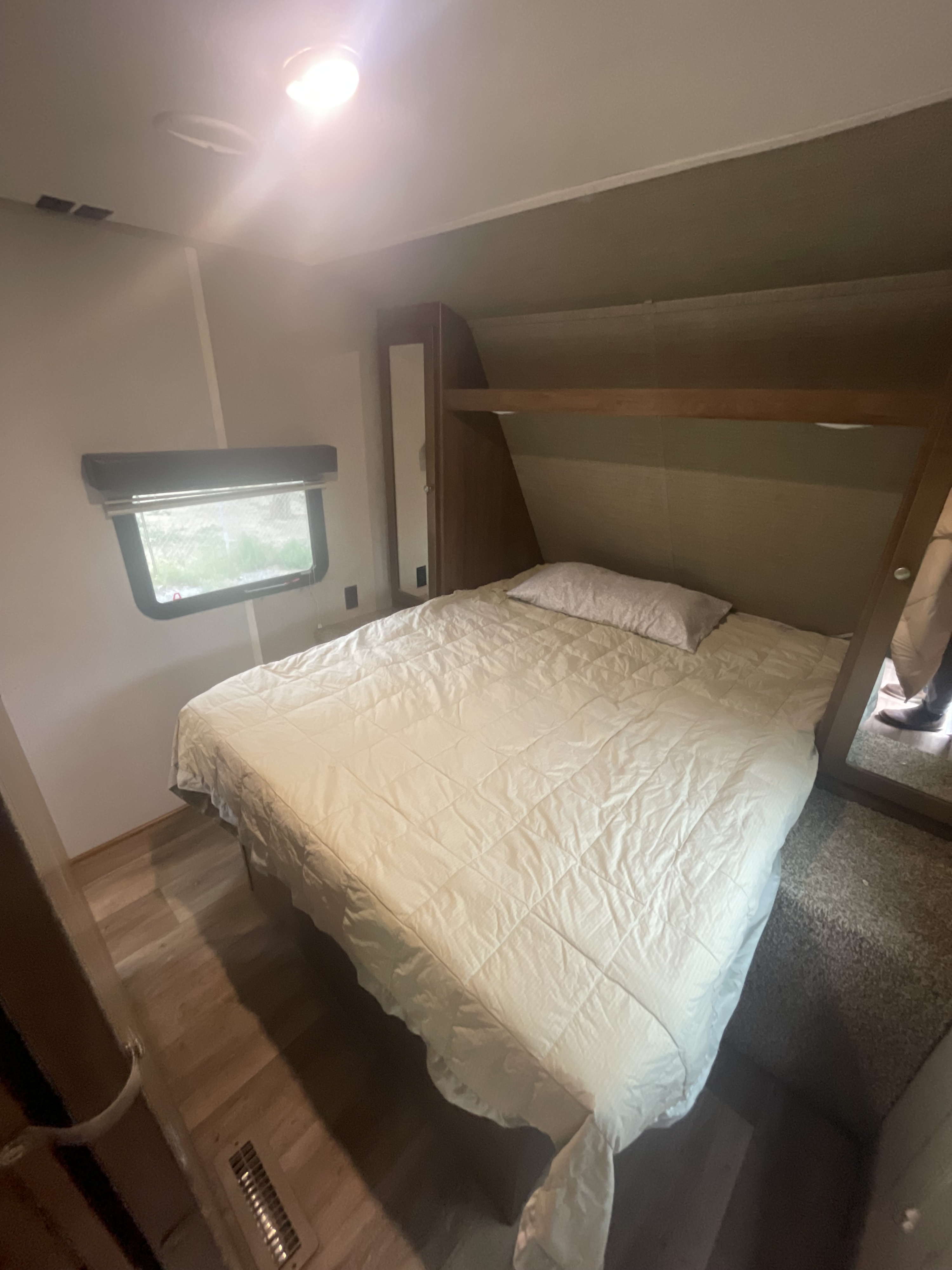 RV rental bedroom interior: a cozy quilted bed, window, and built-in storage. Bright, compact space for your travels.. Keystone RV Aspen Trail 2019