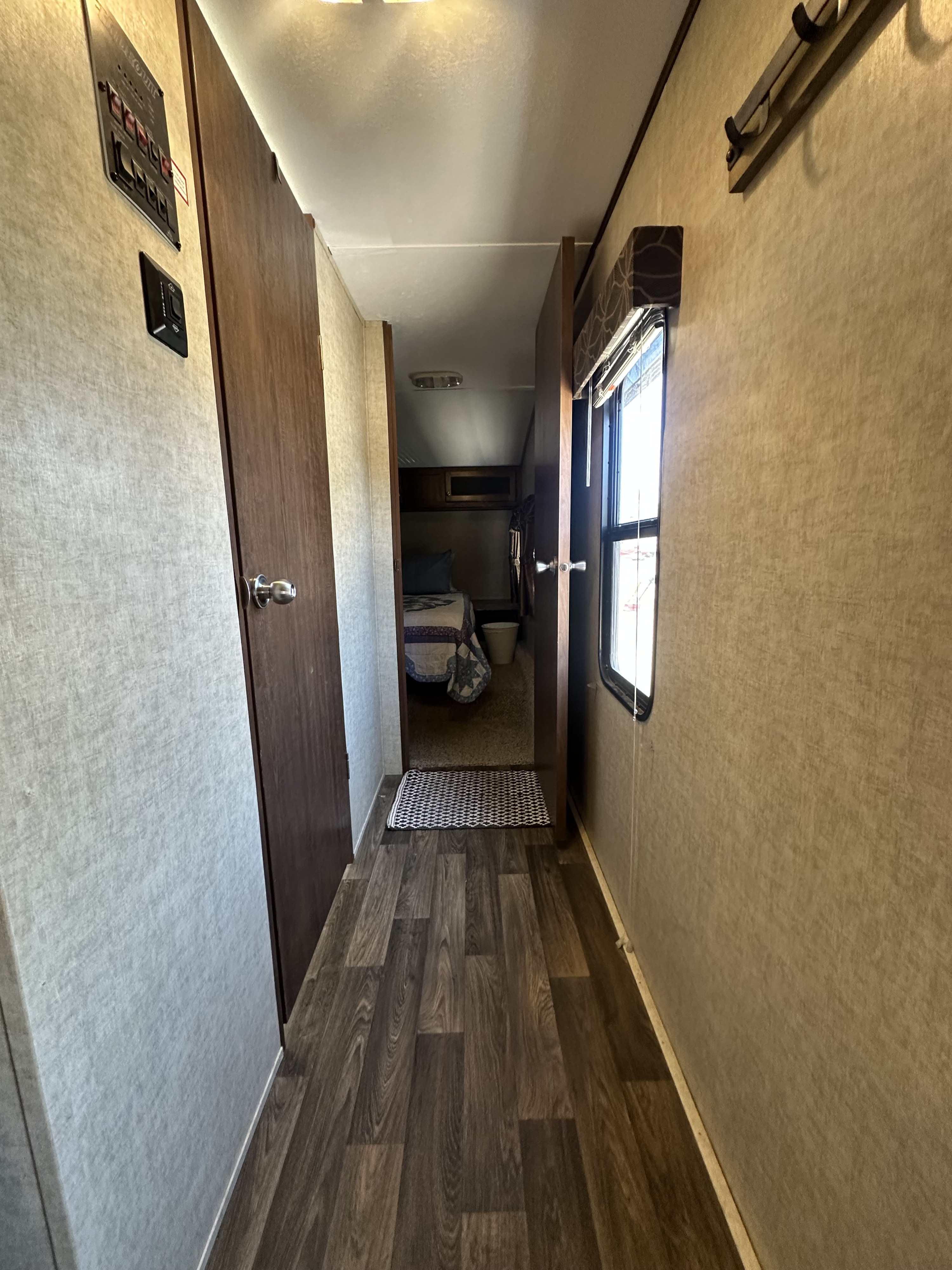 Hallway of an RV rental, showing a control panel, window, and a glimpse into the bedroom.. Keystone RV Hideout 2016