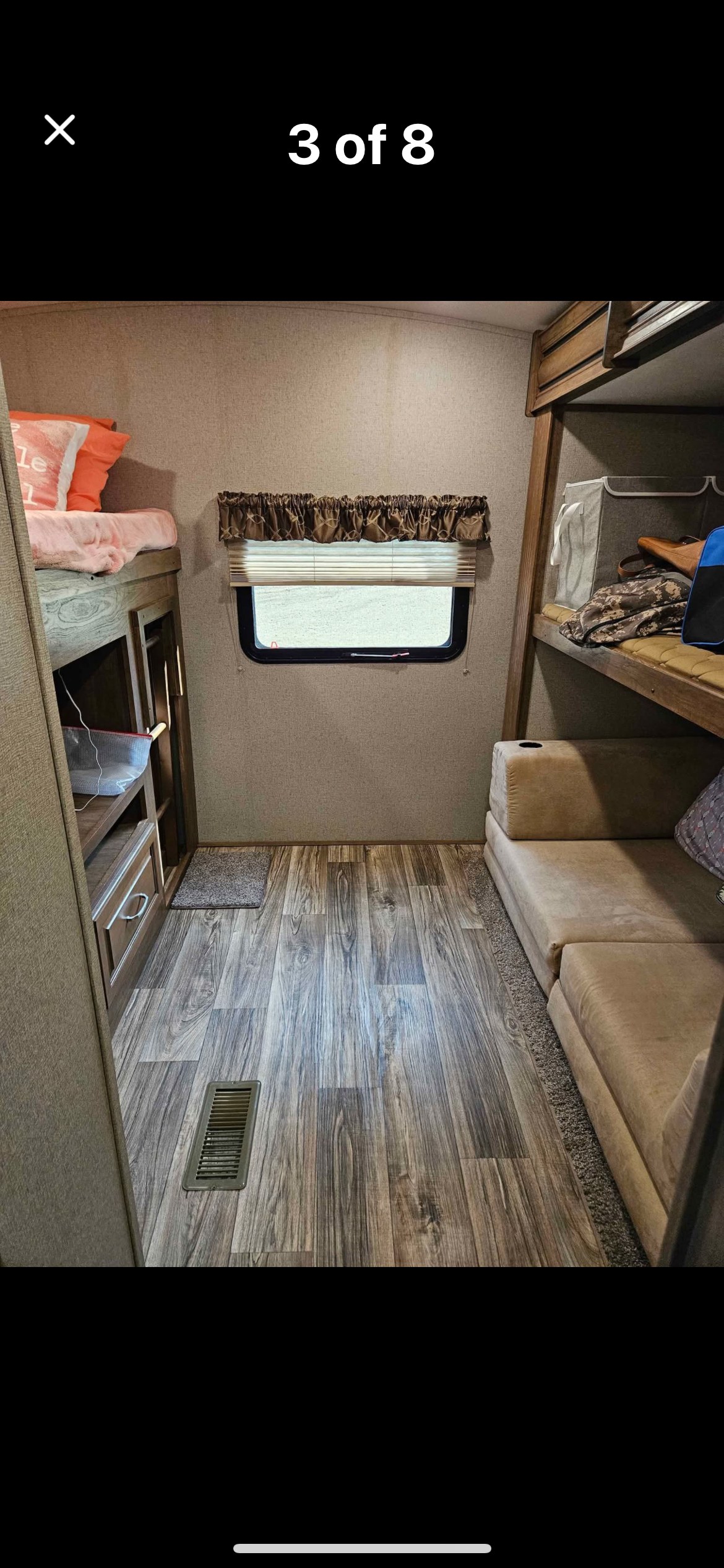 RV rental interior: bunk beds, window, wood-look floor, and sofa. A compact, functional living space.. Keystone RV Laredo 2019