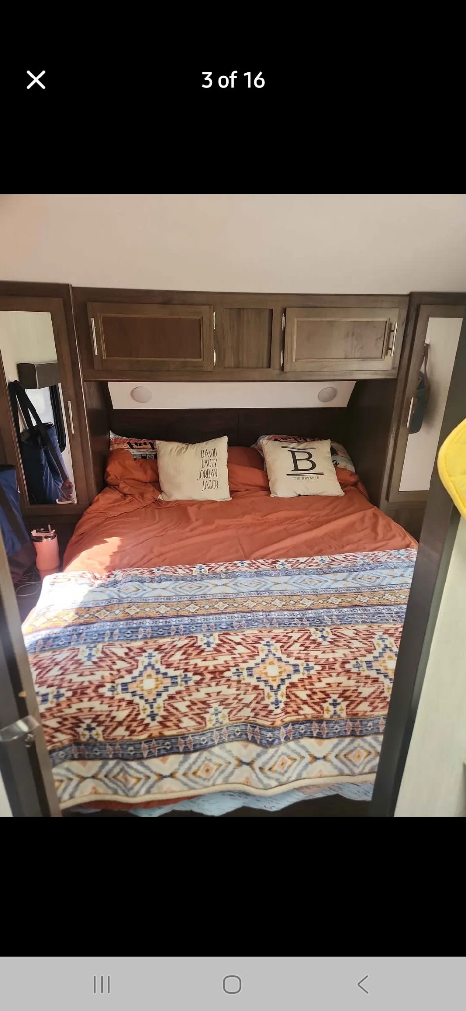 RV rental bedroom showcasing a cozy bed with orange sheets, a patterned blanket, and built-in storage cabinets.. Forest River Cherokee 2020