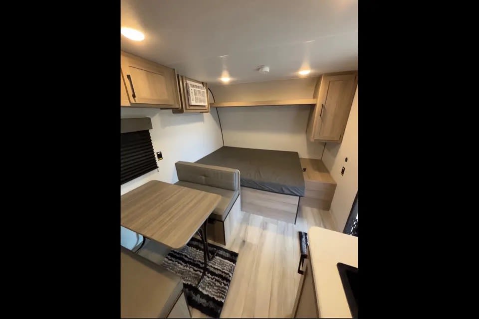 Compact RV rental interior with a cozy bed, dinette, and kitchenette. Perfect for your next adventure.. Keystone Coleman 17B 2025