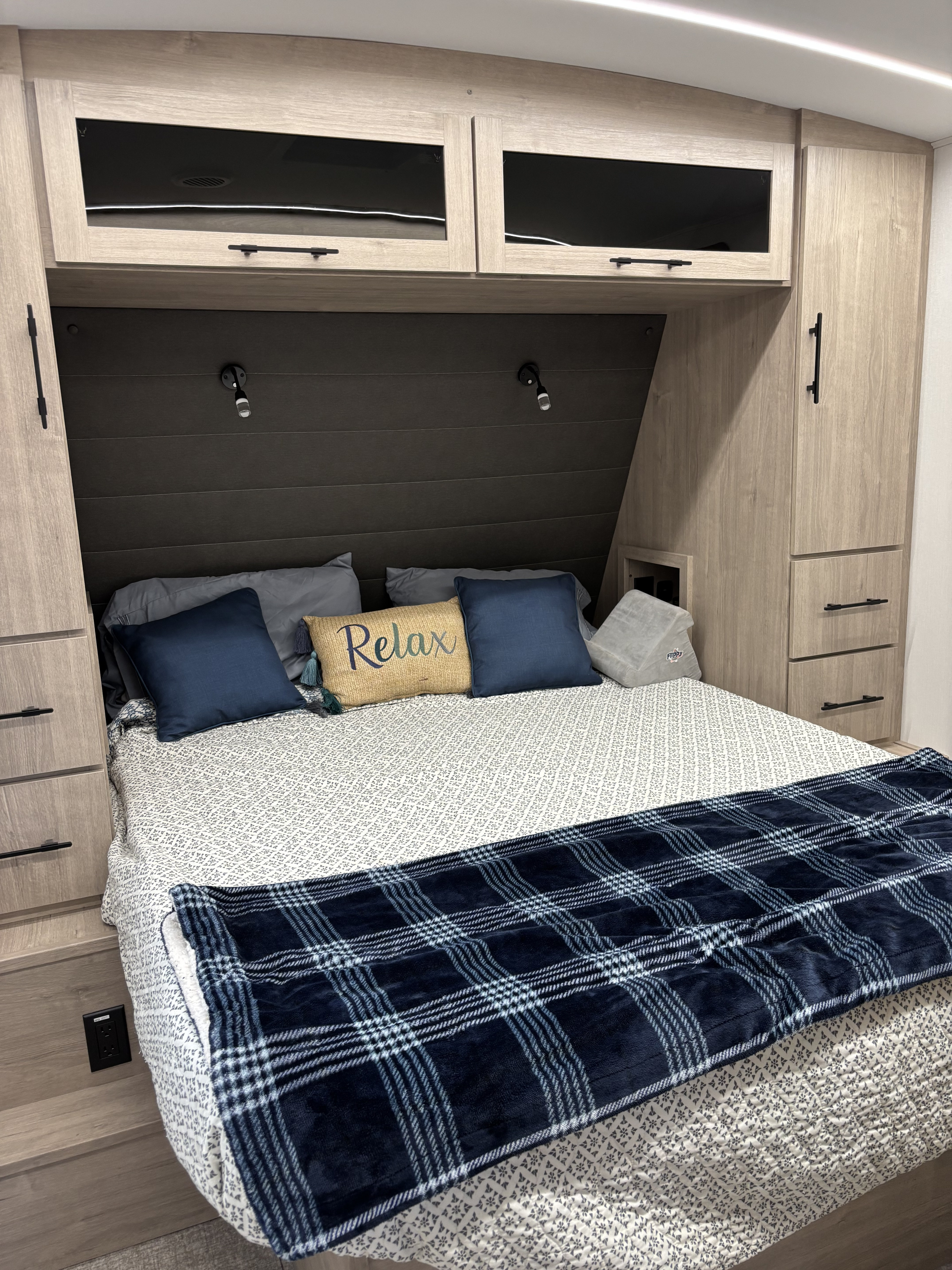 This RV rental bedroom features a comfy bed with blue bedding, ample built-in storage, and overhead cabinets.. Imagine 2300MK 2025