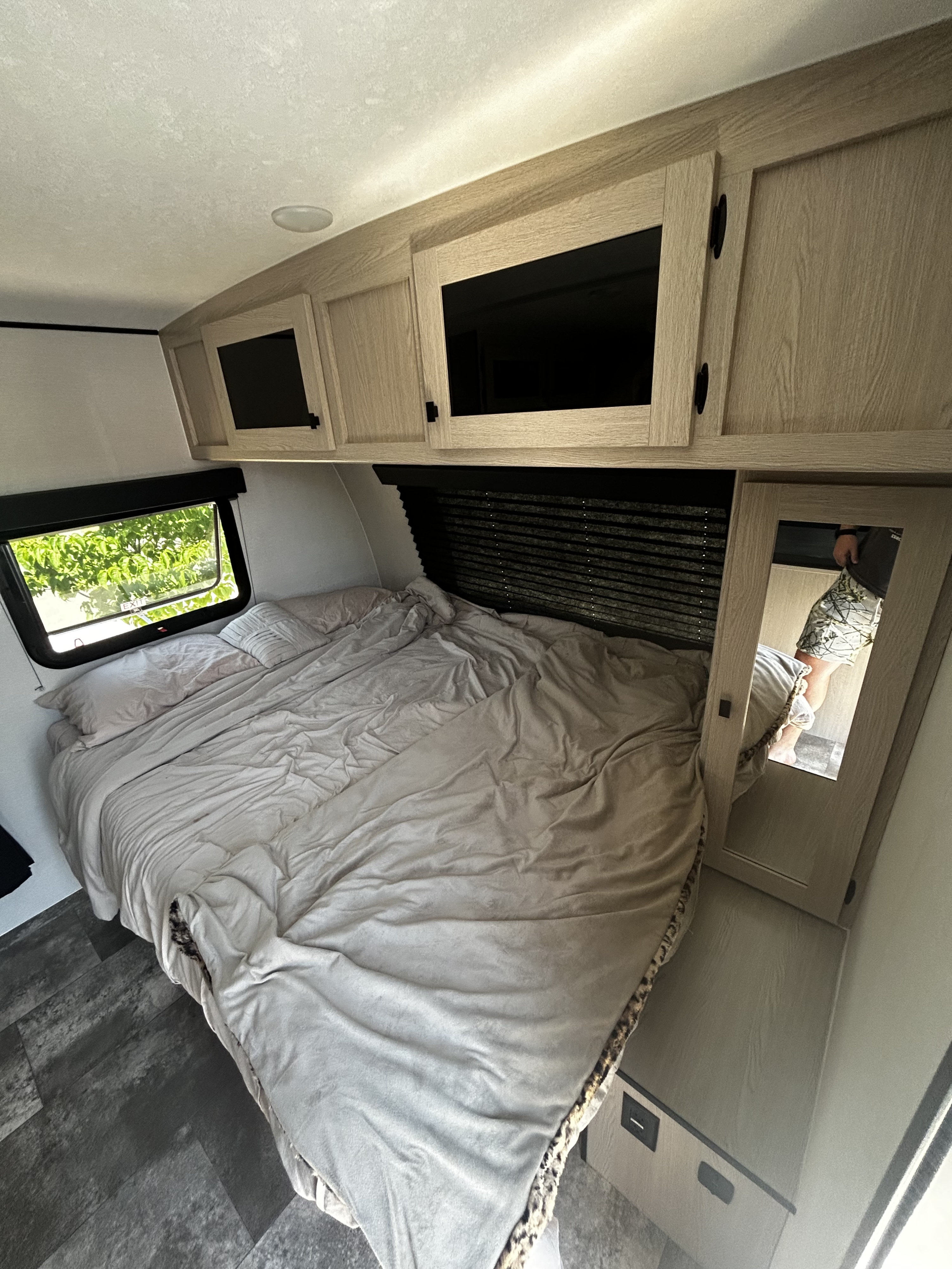 Cozy RV rental bedroom with light bedding, overhead storage, a window, and mirror, designed for comfortable travel.. Coachmen Apex Nano 2023