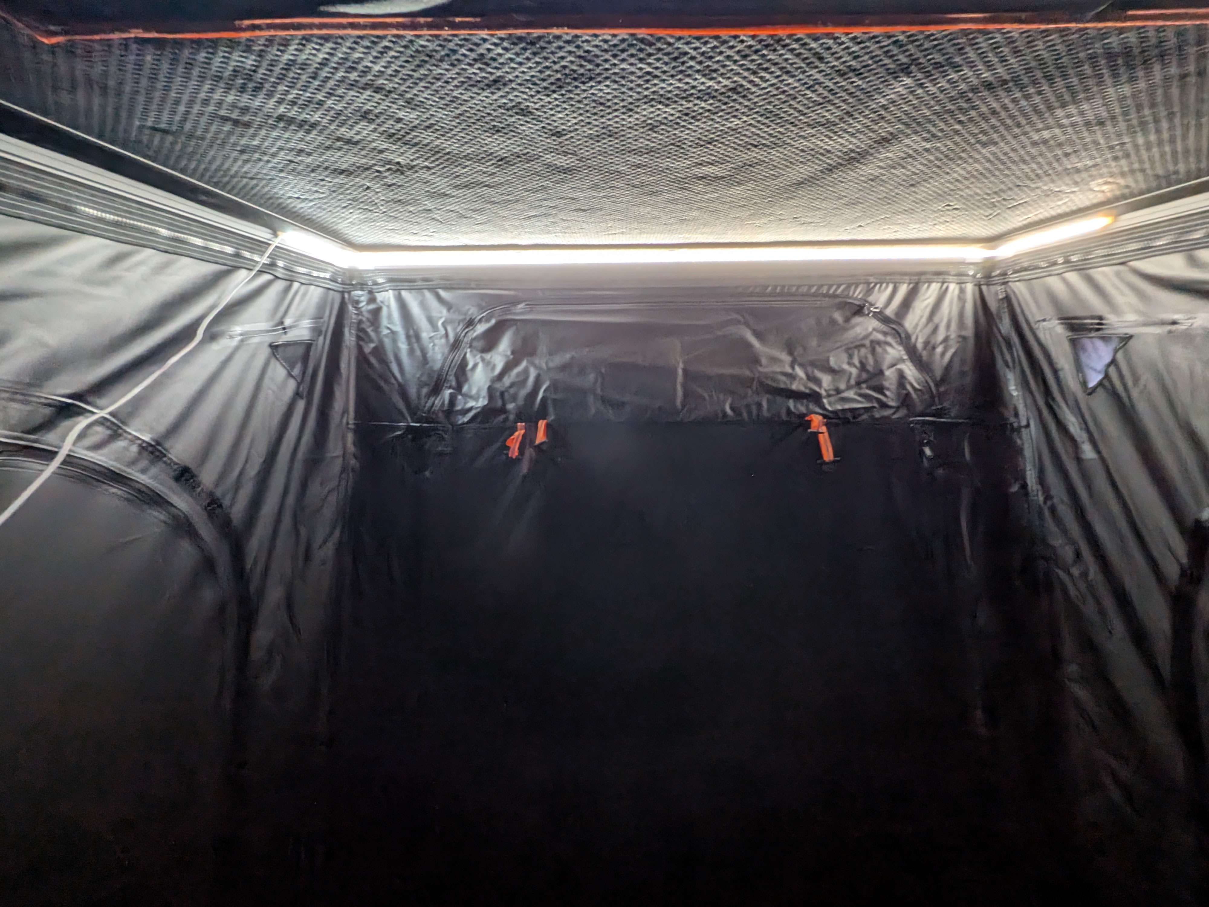 Brightly lit interior of an RV rental sleeping area with textured ceiling & dark fabric walls. LED strip provides illumination.. Toyota Sienna 2012