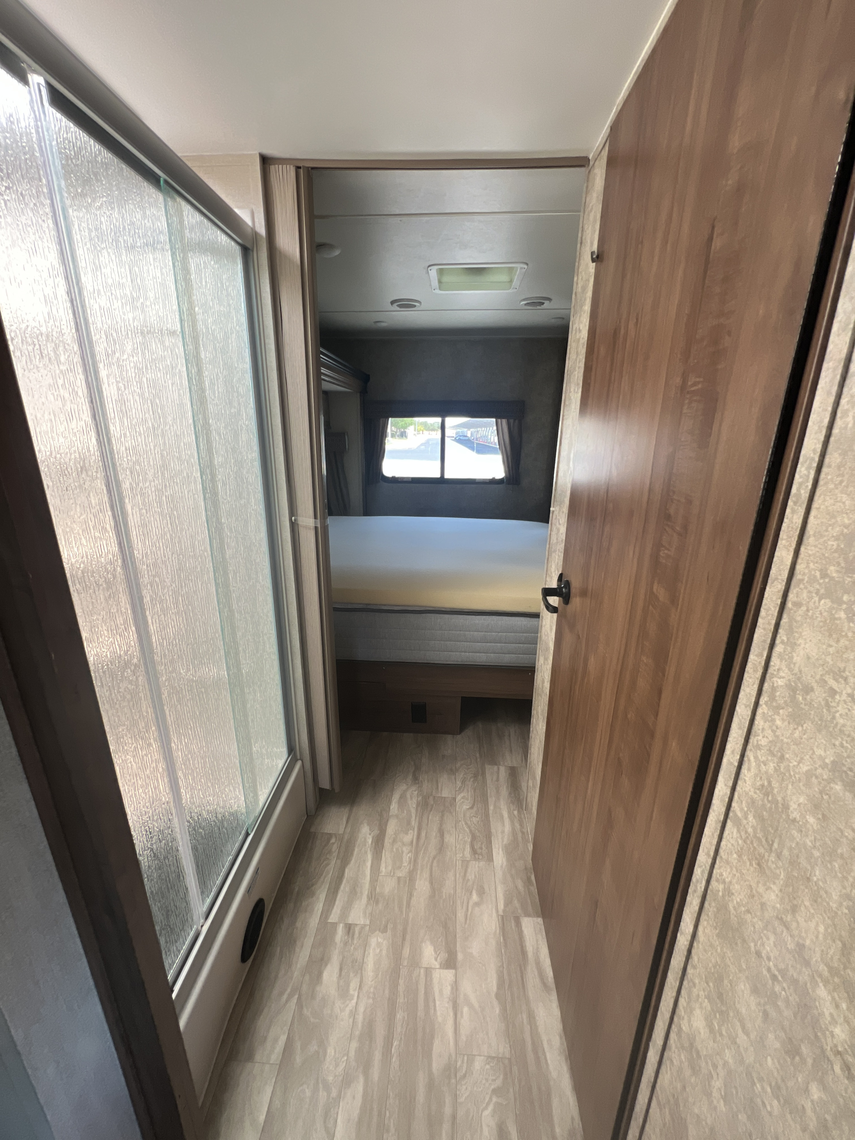 Navigate this inviting RV rental interior: a hallway connects a textured glass shower on the left to a private bedroom straight ahead.. Gulf Stream Conquest 2019