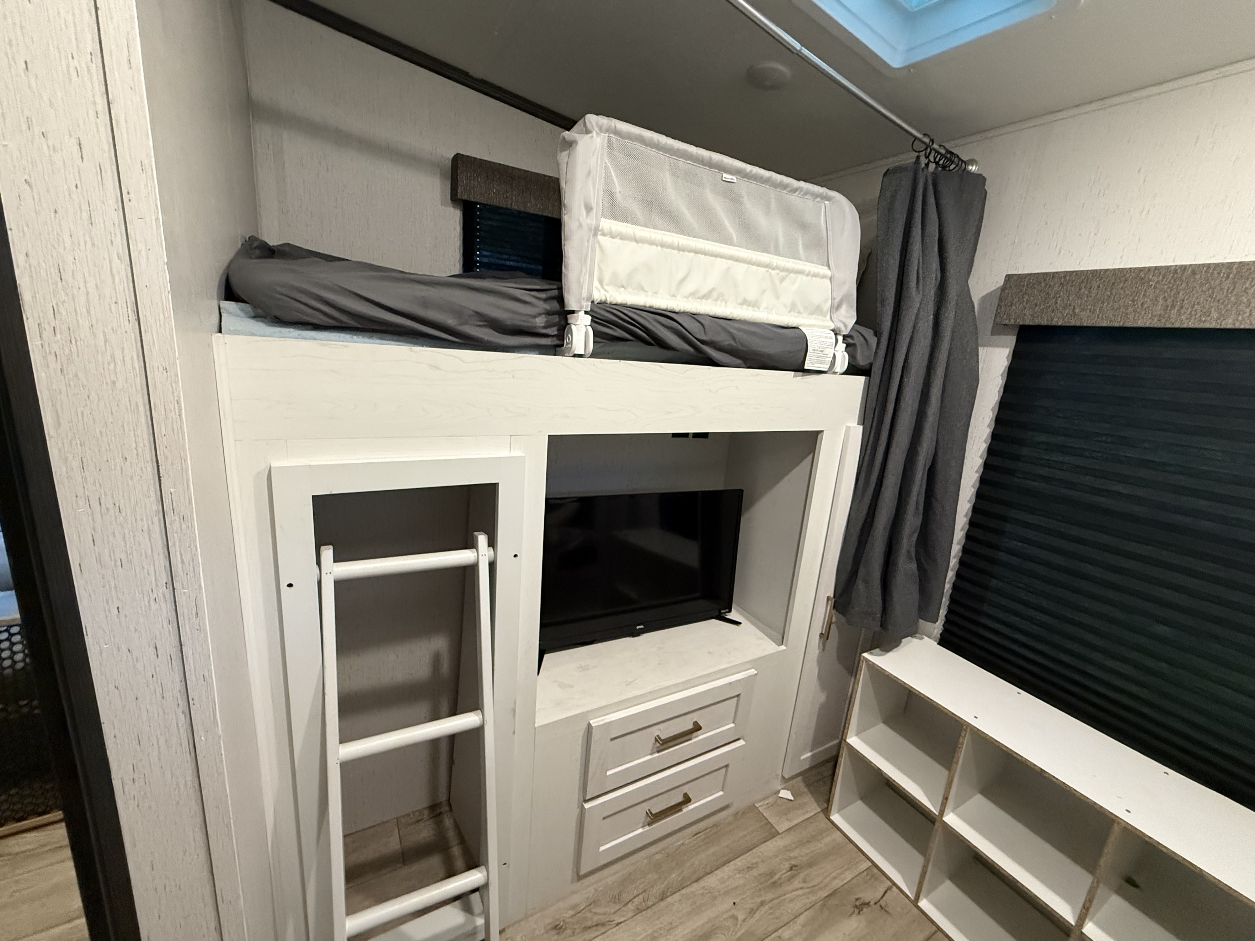 Inside an RV rental: bunk beds with a safety rail, ladder, TV, and storage for a comfortable family sleeping area.. Astoria Astoria Fifth Wheel 2023