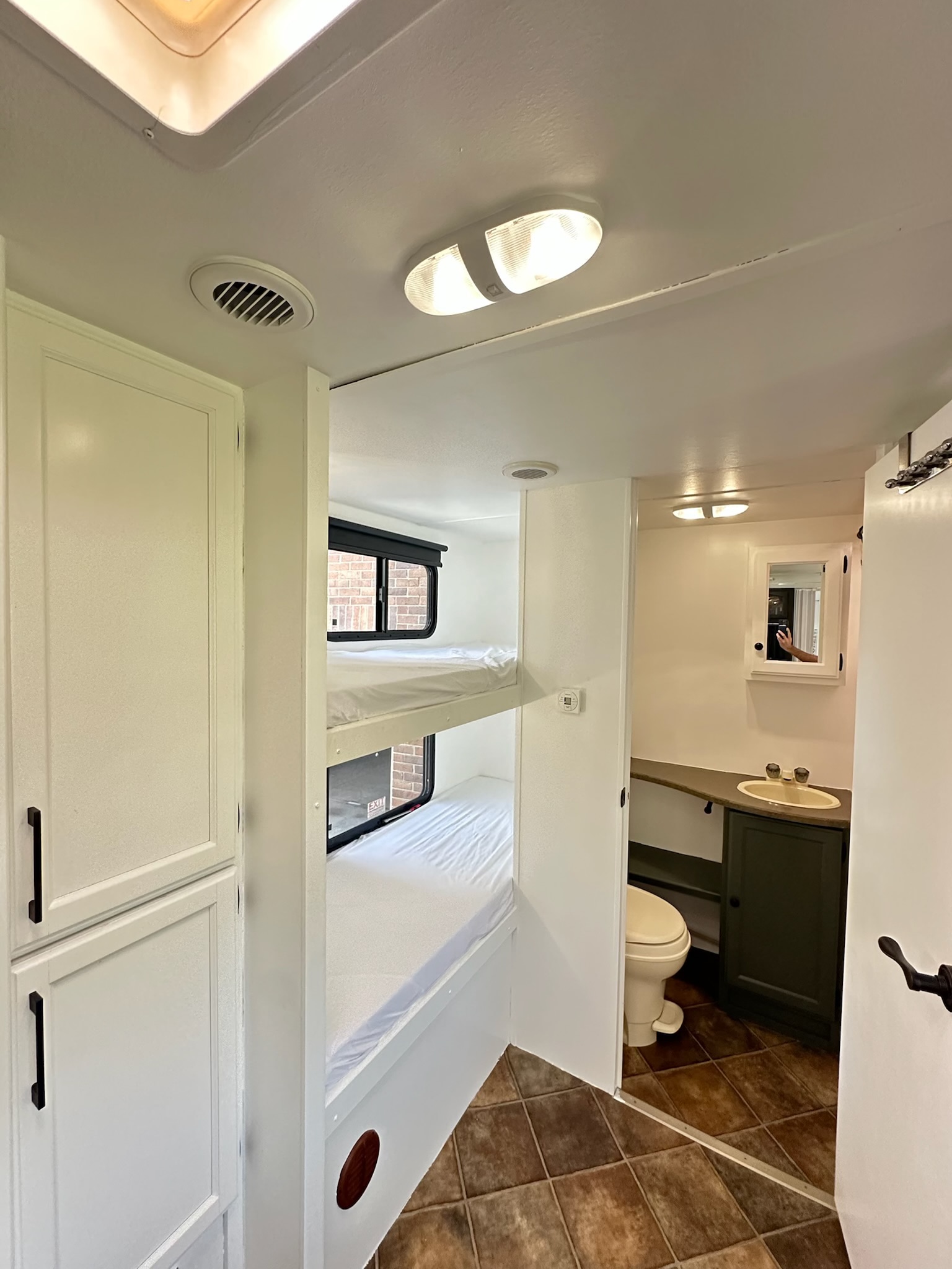 Spacious RV rental interior featuring bunk beds, a bathroom with sink and toilet, plus built-in storage.. Keystone RV Passport GT 2011