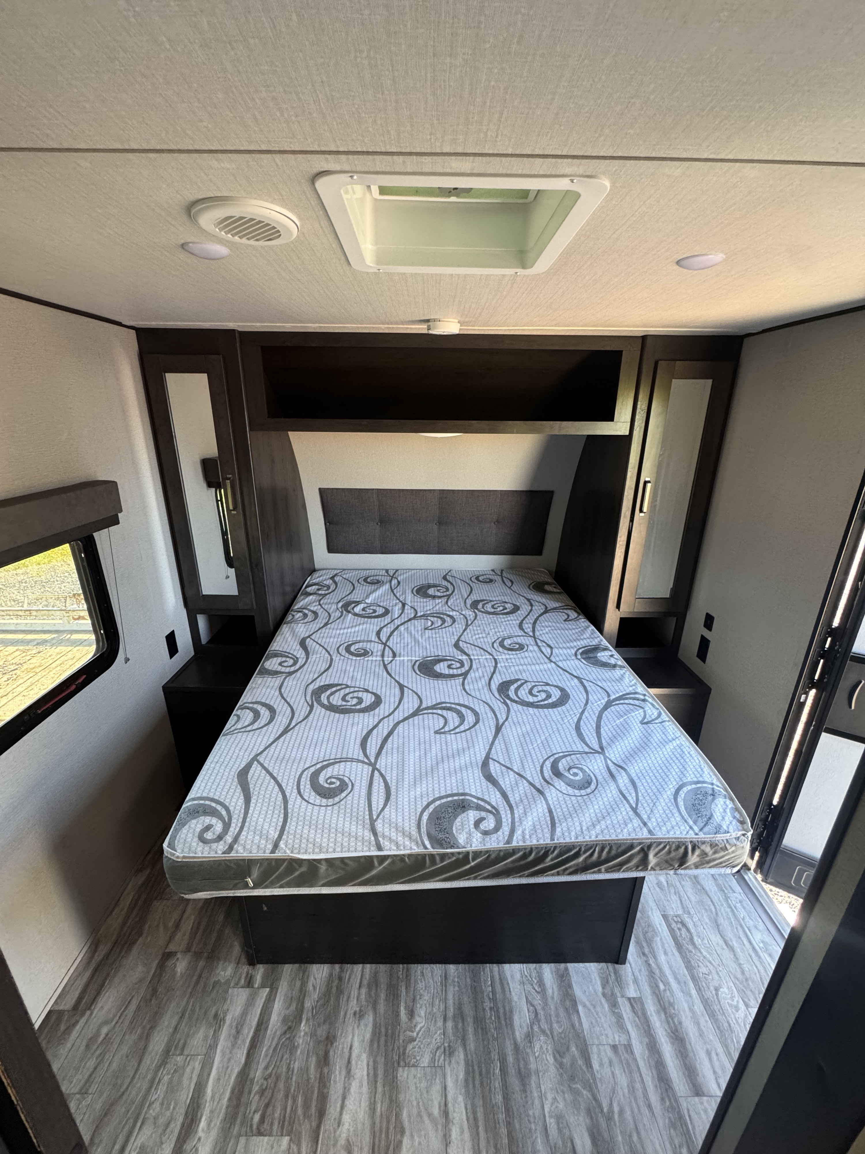 Step into this modern **rv rental** bedroom, with a comfortable bed, built-in storage, and bright interior lighting.. Grand Design Transcend Xplor 2021