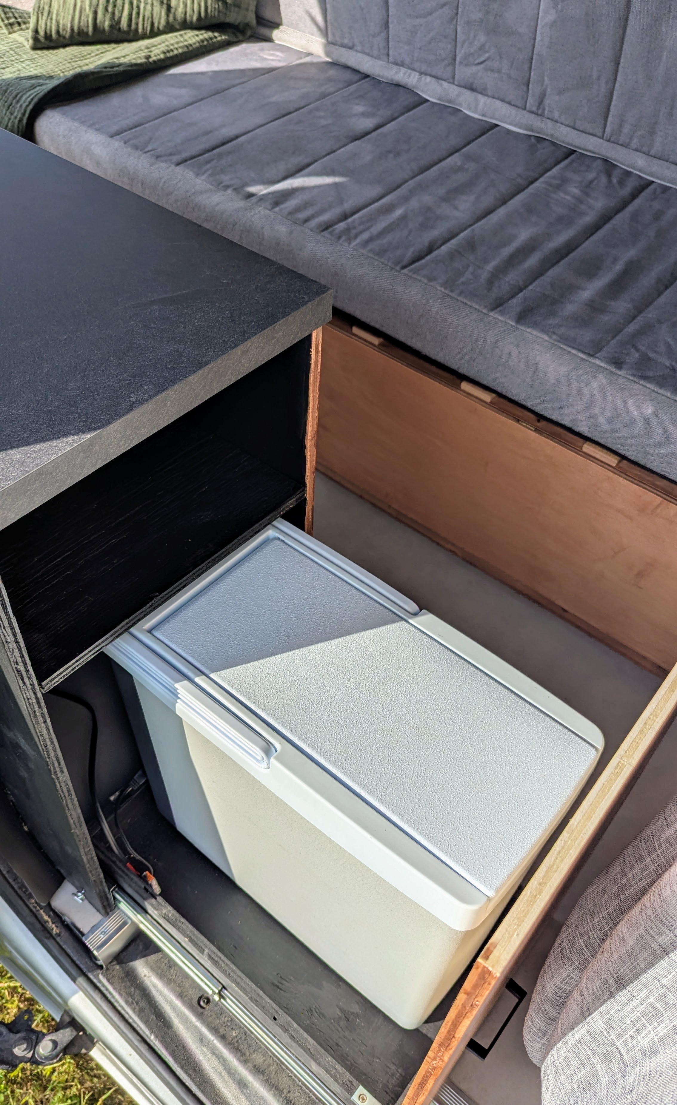 Inside an RV rental: a flexible seating/bed area, built-in storage, and a compact cooler, maximizing camper utility.. Ram Promaster City 2015