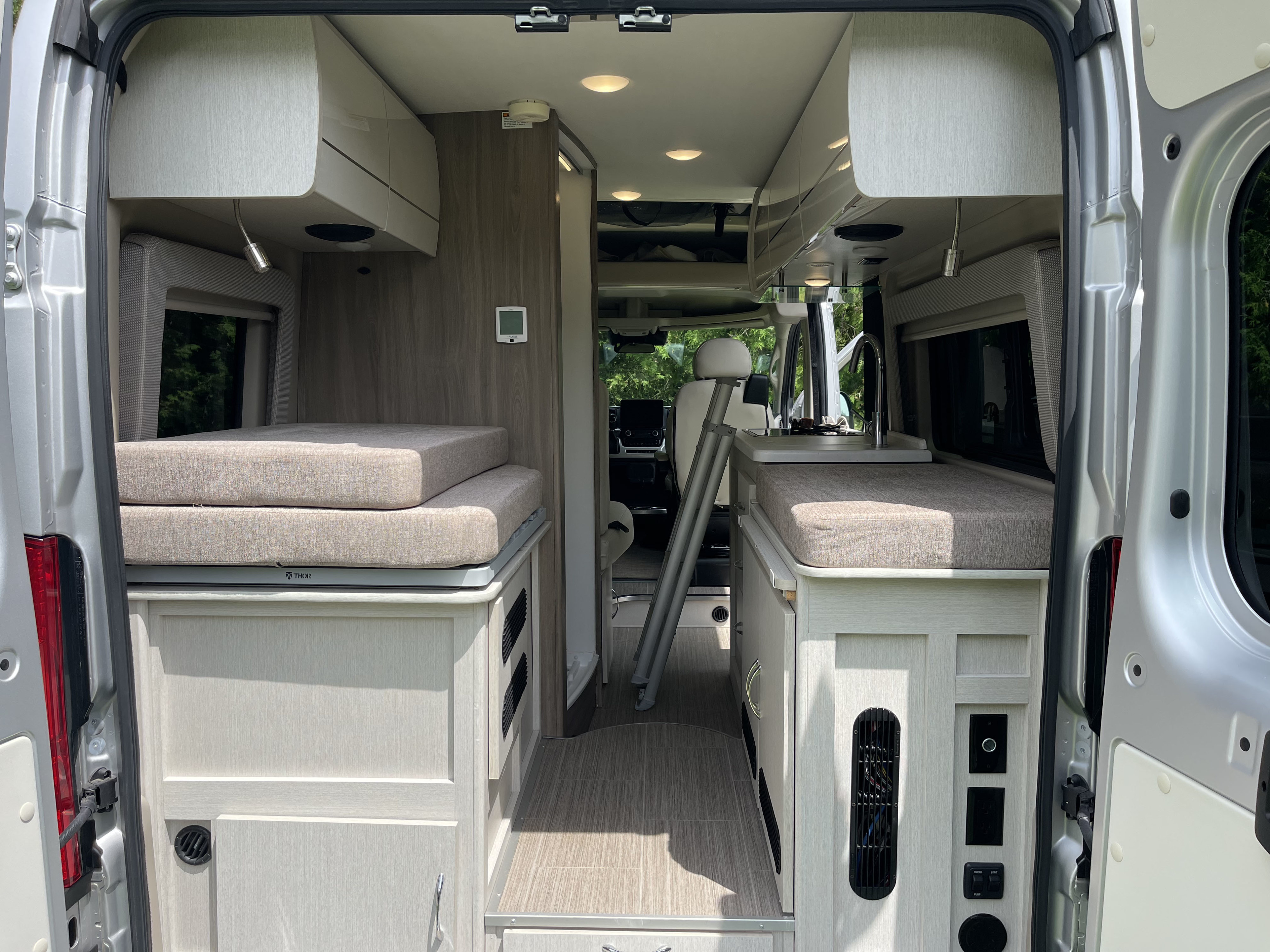 Spacious rv rental camper van interior. Features light wood cabinetry, comfy beds, compact kitchen sink, and full living area.. Thor Rize 2023
