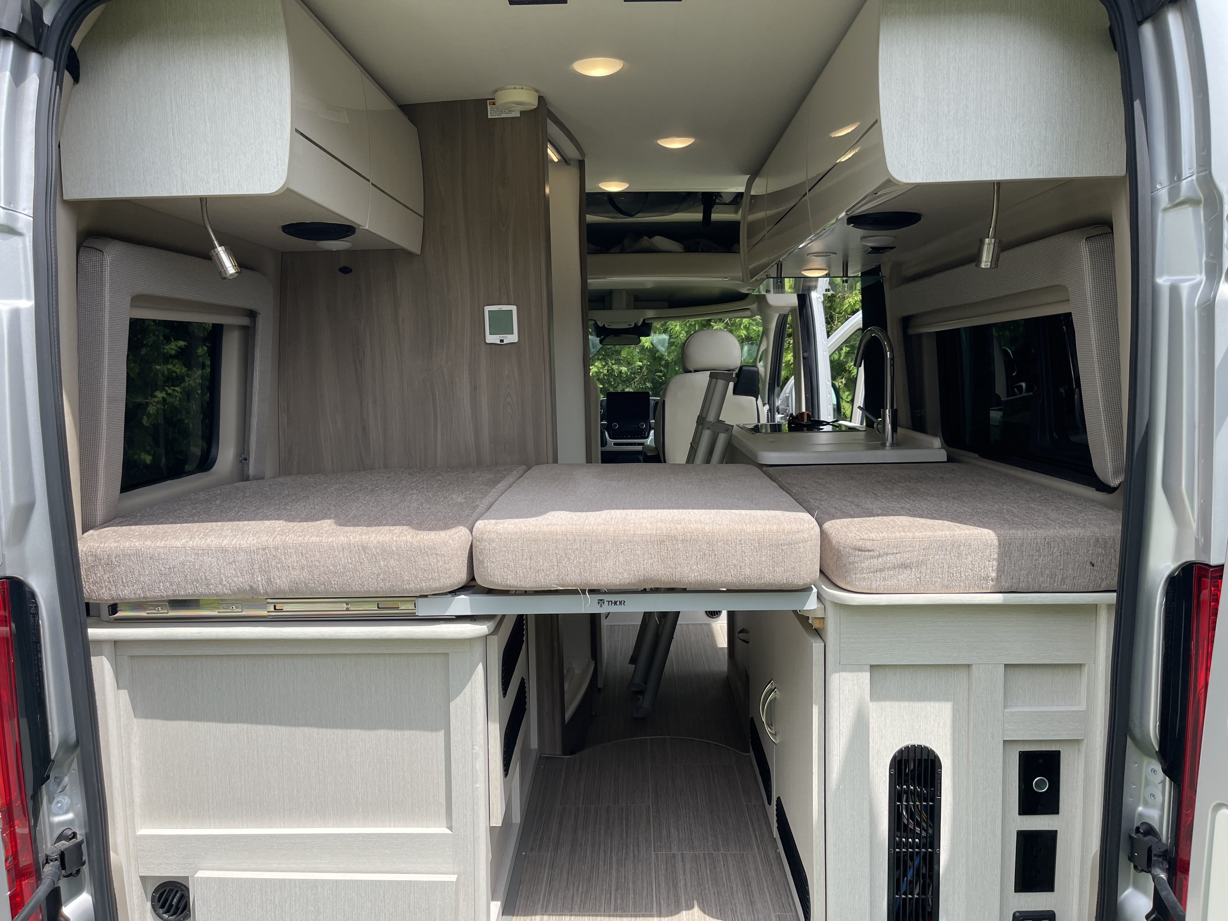 RV rental: View inside a modern camper van with rear beds, a compact kitchen, and storage. Ideal for adventure.. Thor Rize 2023