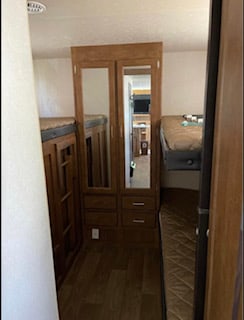 RV rental bunk room: Two sets of wooden bunk beds flank a central mirrored wardrobe, providing sleeping and storage for travel.. Forest River Salem Cruise Lite 2018