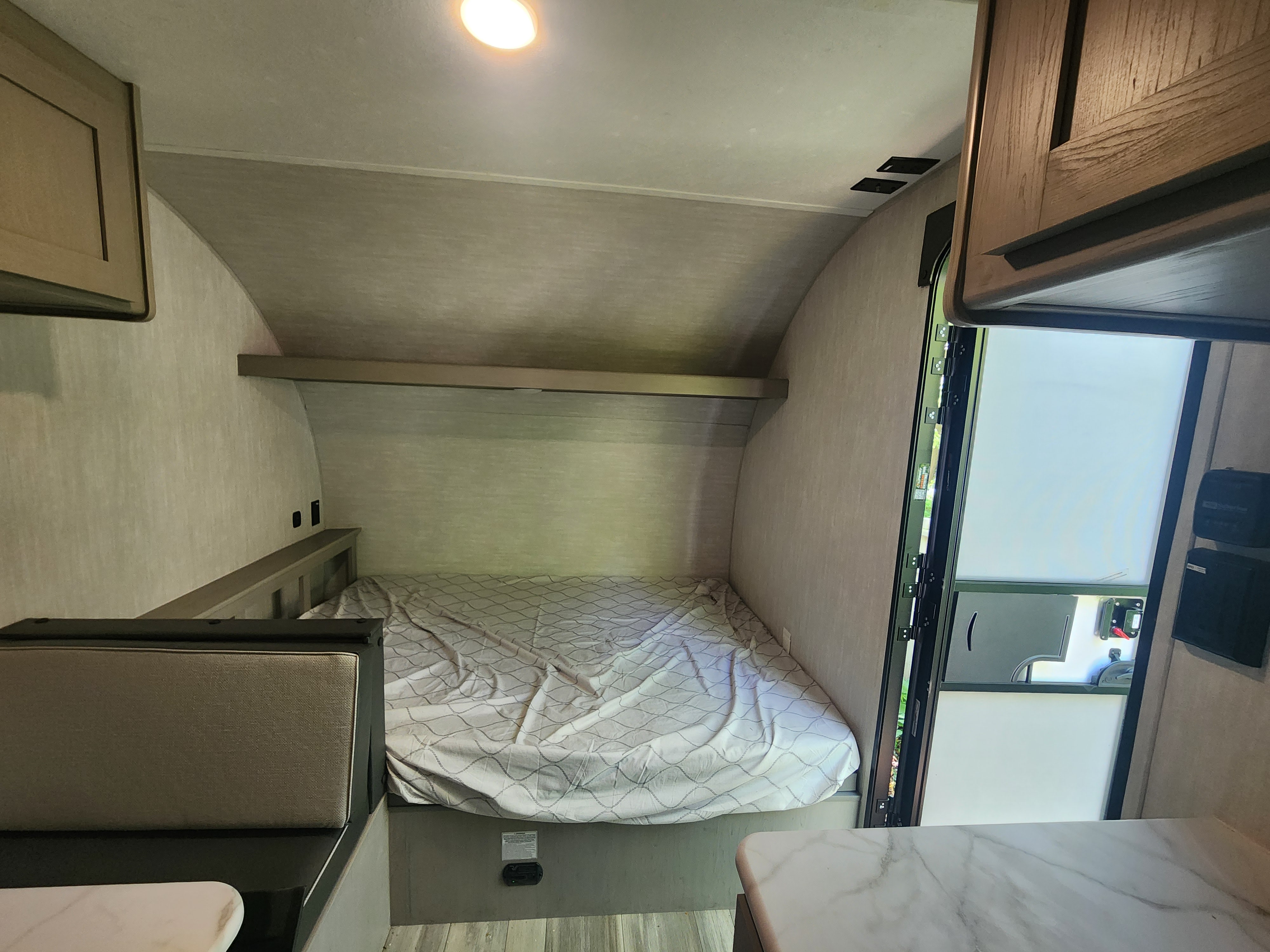 Compact RV rental interior featuring a cozy bed, dinette, and open door to nature. Ideal for adventures.. Coachmen RV Clipper 3k 2025