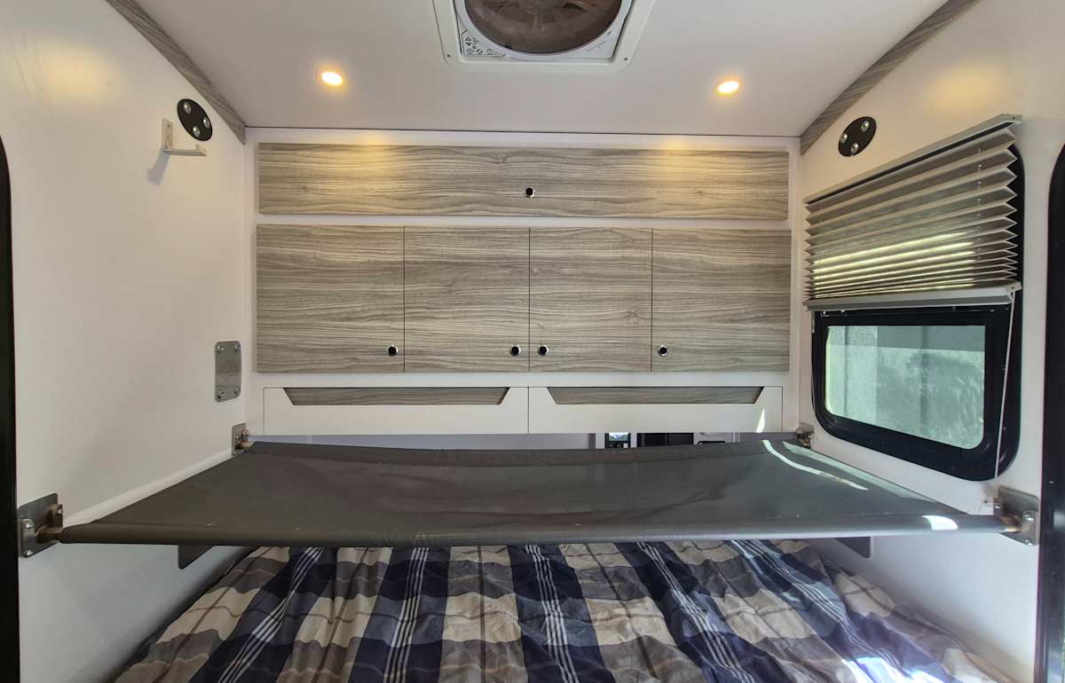 RV rental interior: Plaid bed, suspended bunk/storage, cabinets, and ceiling fan provide comfort for travelers.. Bean Trailer Mean Bean 2022