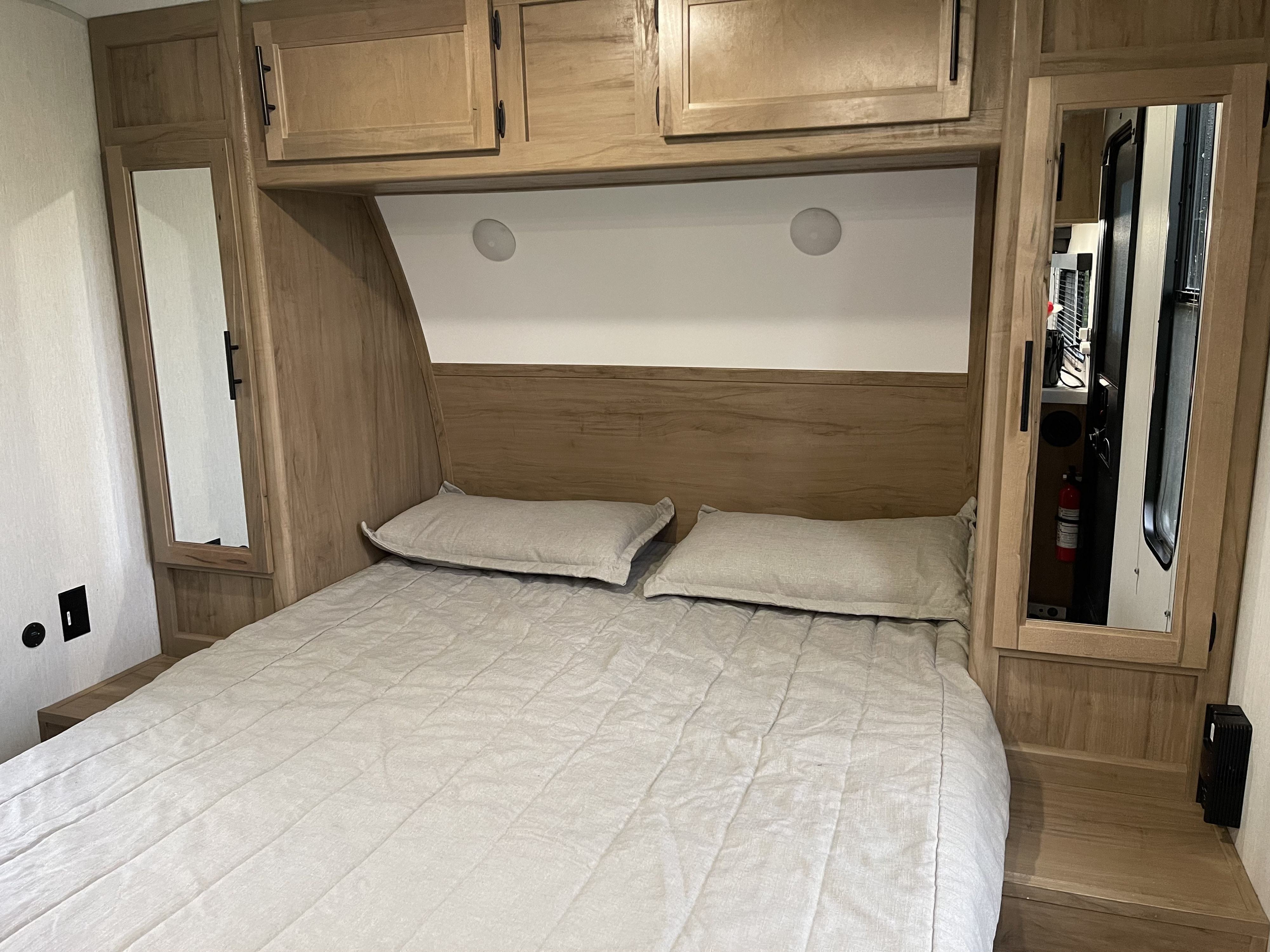 Cozy RV rental bedroom features a comfortable bed, overhead storage, mirrored cabinets, and ceiling lights.. Forest River Cherokee Grey Wolf 2024