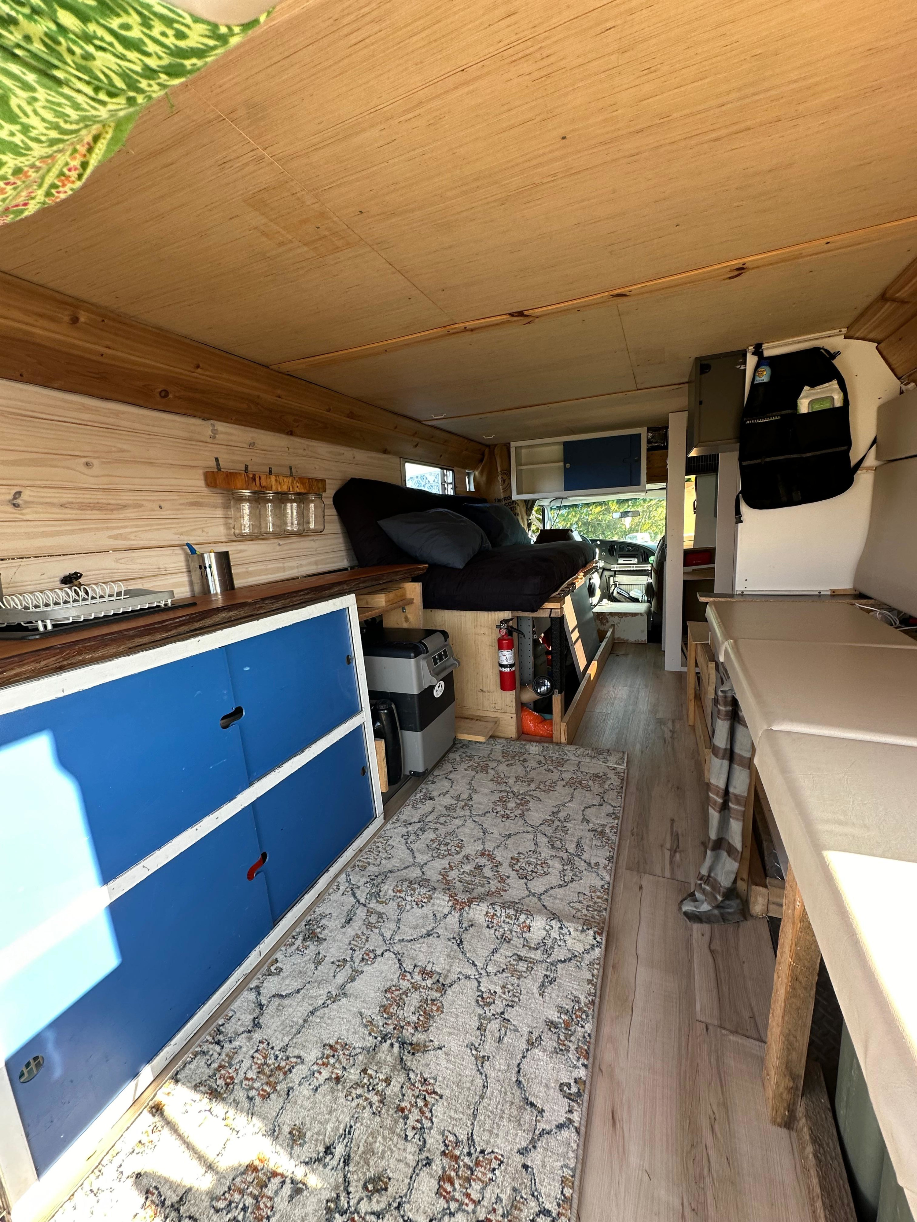 Step inside this RV rental! Custom van conversion with cozy bed, kitchen space, and wood interior.. Ford E350 Box Van 2003