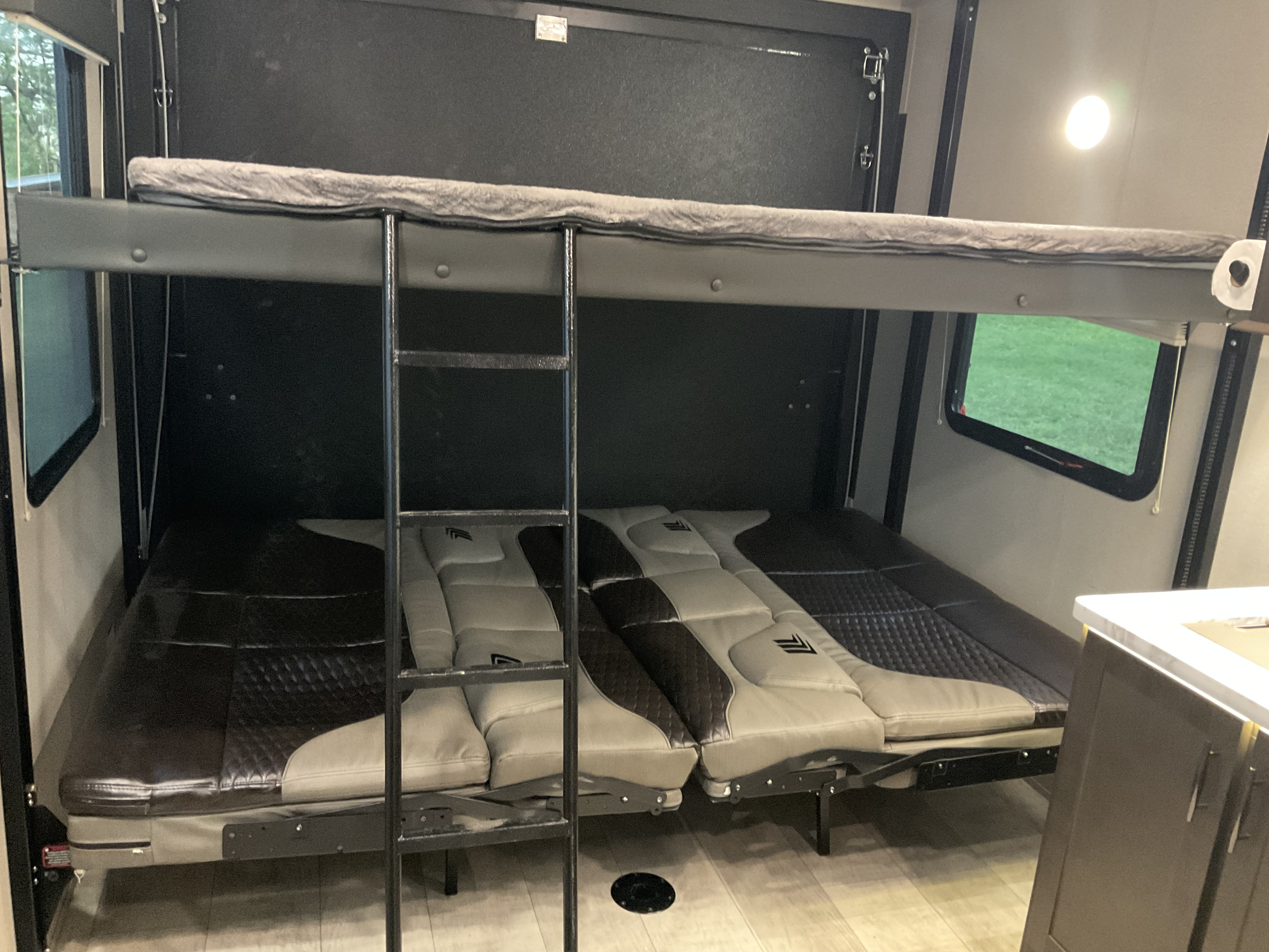 Spacious RV rental interior featuring convertible bunk beds with a ladder. Perfect for family adventures.. Grand Design Momentum 2021
