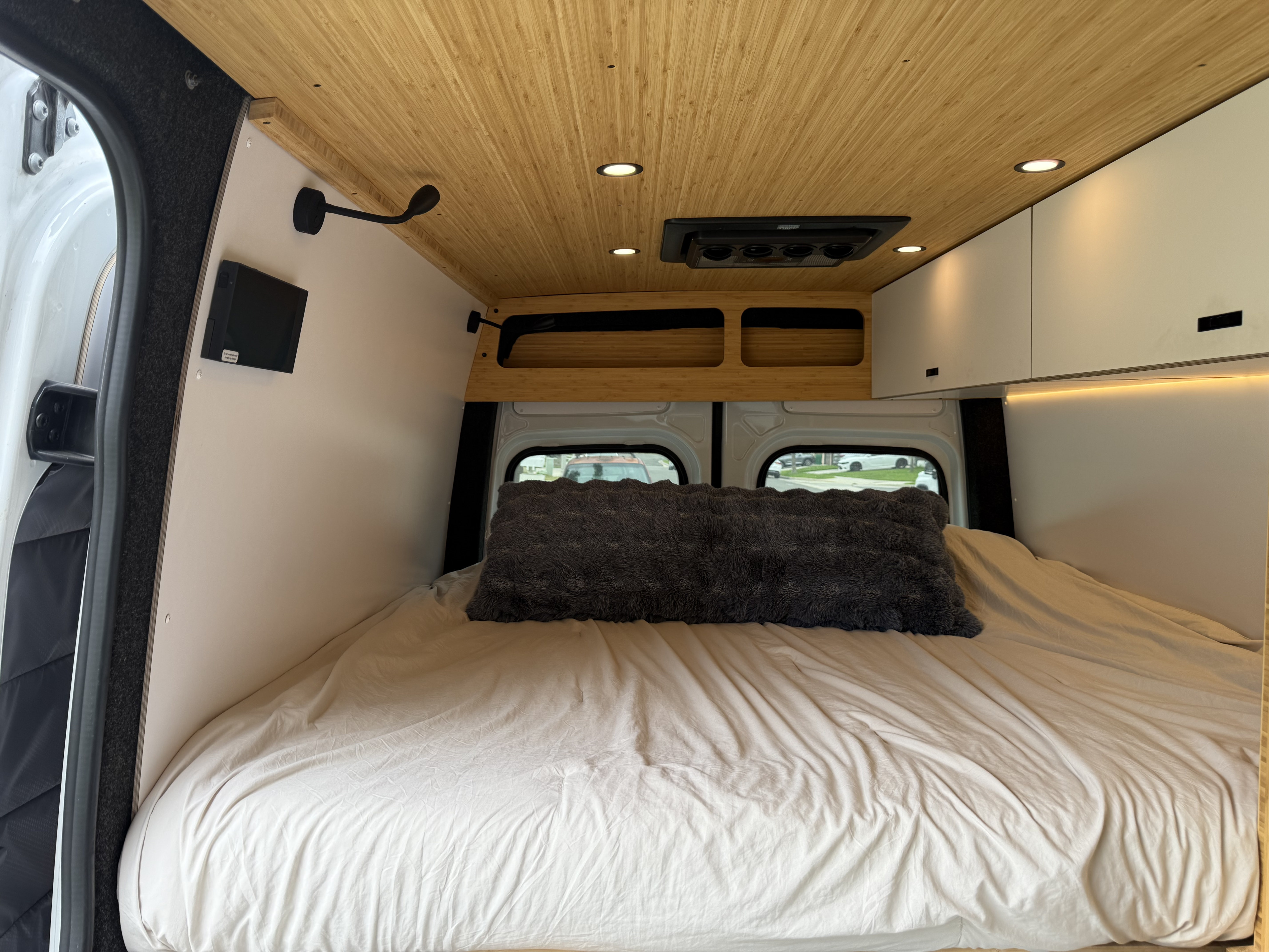 Cozy RV rental bedroom in a camper van, featuring a large bed, bamboo ceiling with lights, and integrated storage for comfortable travel.. Mercedes-Benz Sprinter 2024