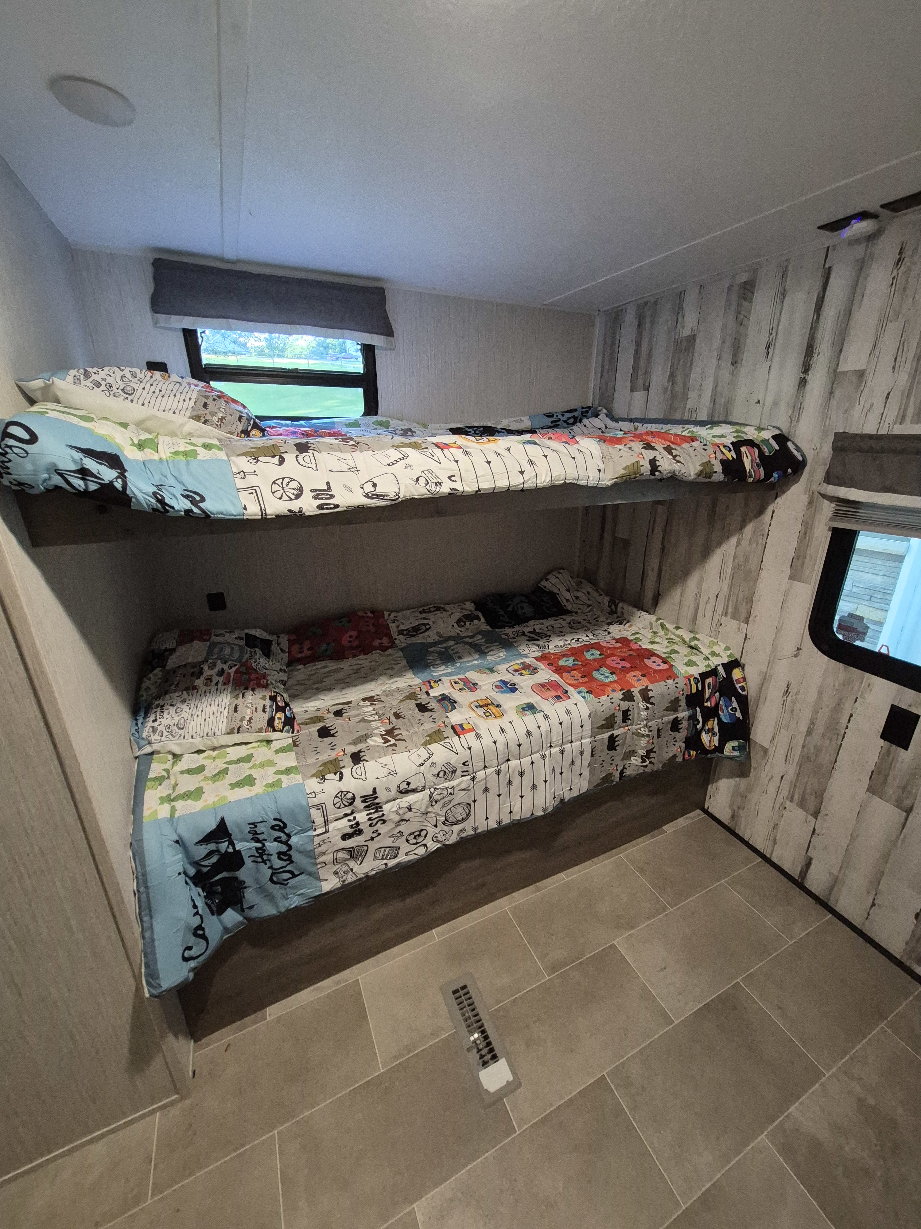 RV rental bunk beds: A cozy interior with colorful, patterned quilts and pillows on two bunks.. Forest River Palomino Puma XLE Lite 2021