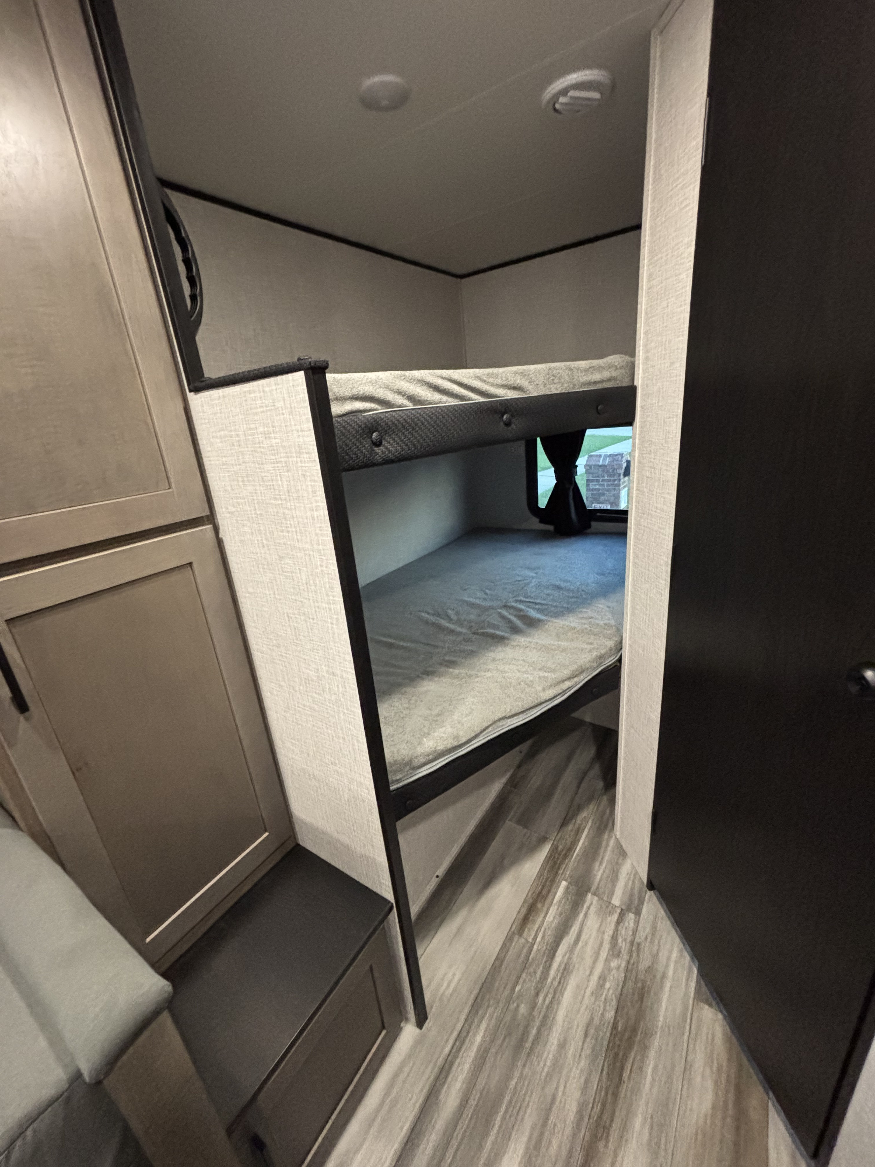 RV rental bunk beds with grey mattresses & storage, offering a cozy sleeping area. Perfect for family trips in a compact interior.. Jayco Jay Flight SLX 2025