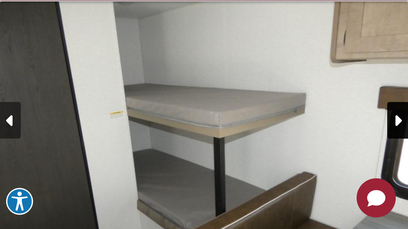 This RV rental shows a compact interior with two comfortable bunk beds, ideal for family sleeping during your travels.. Keystone Springdale 2025