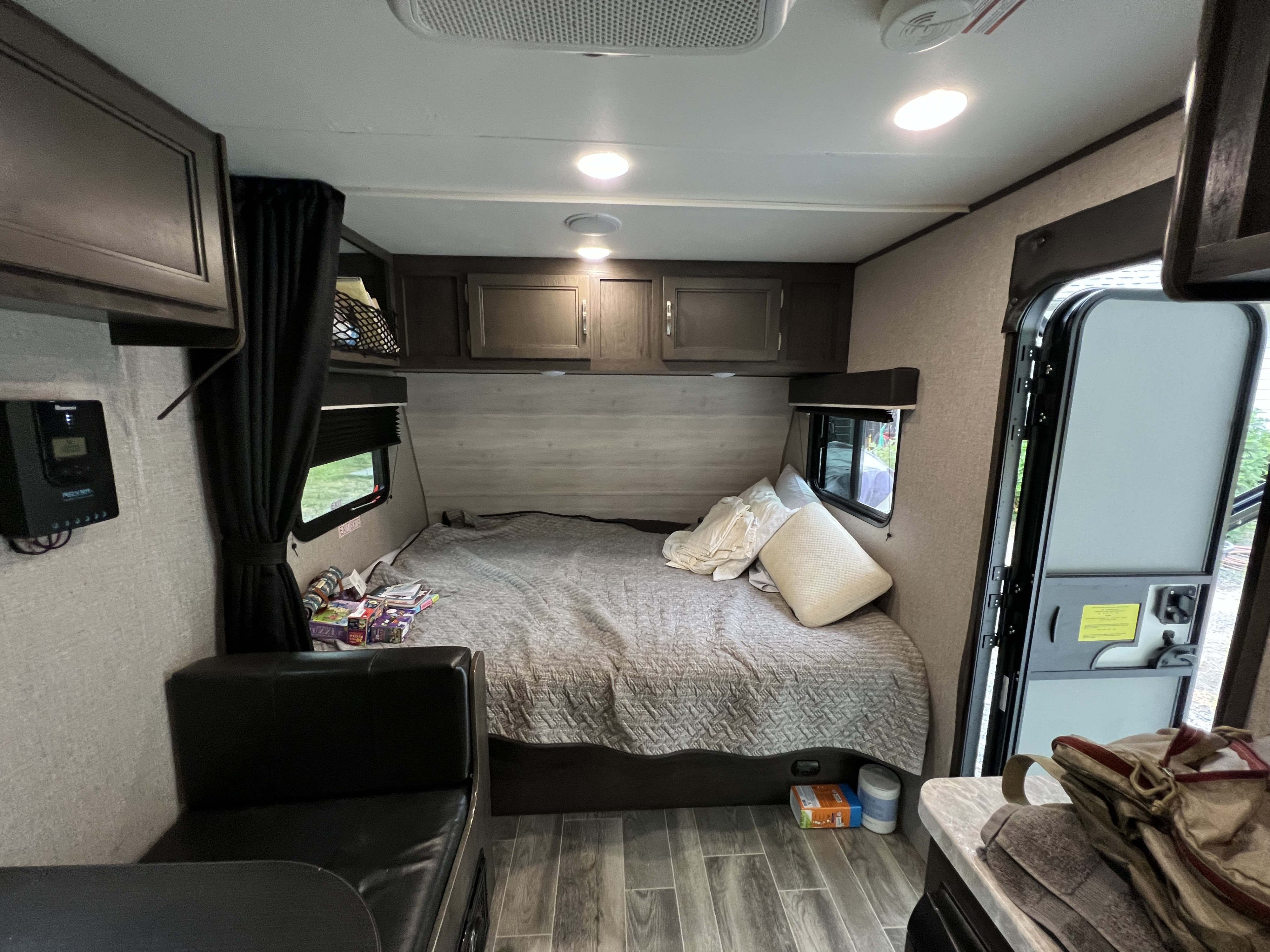 Inside an RV rental: a comfortable bed with overhead storage, a small lounge area, and an entry door.. Jayco Jay Flight SLX Baja Edition 2021