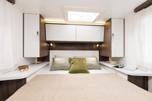 Step inside this cozy RV rental bedroom featuring a comfy bed, overhead cabinets, and a skylight.. BENIMAR T 497 TESSORO 2025