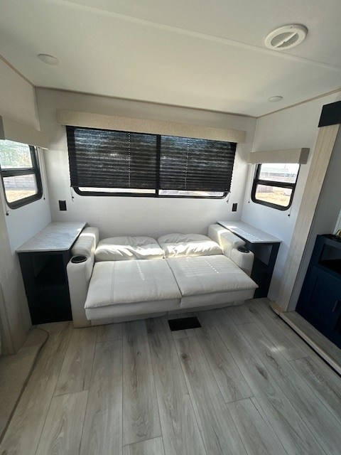 Clean RV rental interior: sofa bed, side tables, large windows with blinds, and light wood floors.. Primetime Avenger 2025