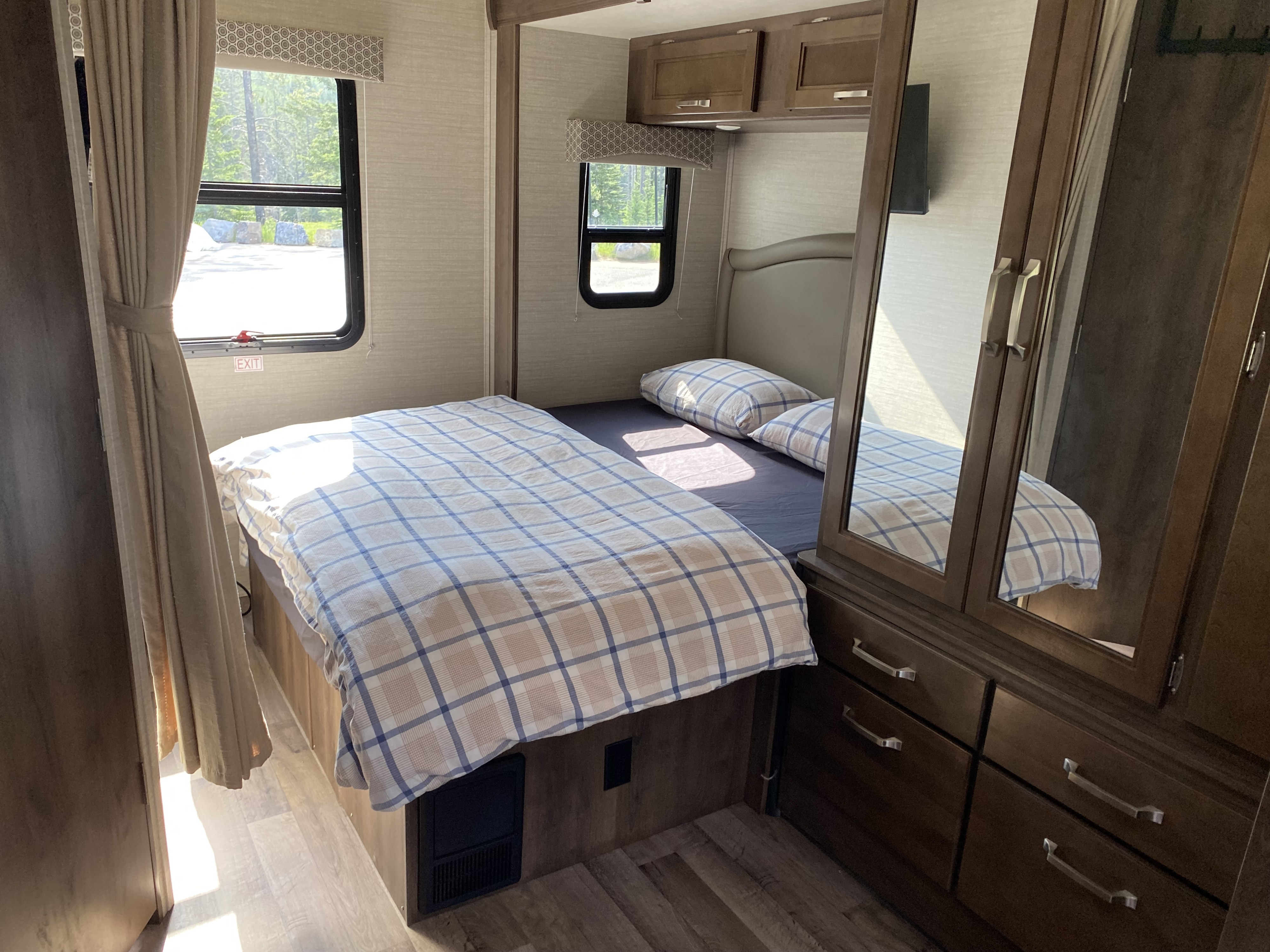 Cozy RV rental bedroom featuring a comfortable bed with plaid bedding, windows, and ample storage.. Jayco Melbourne 2020
