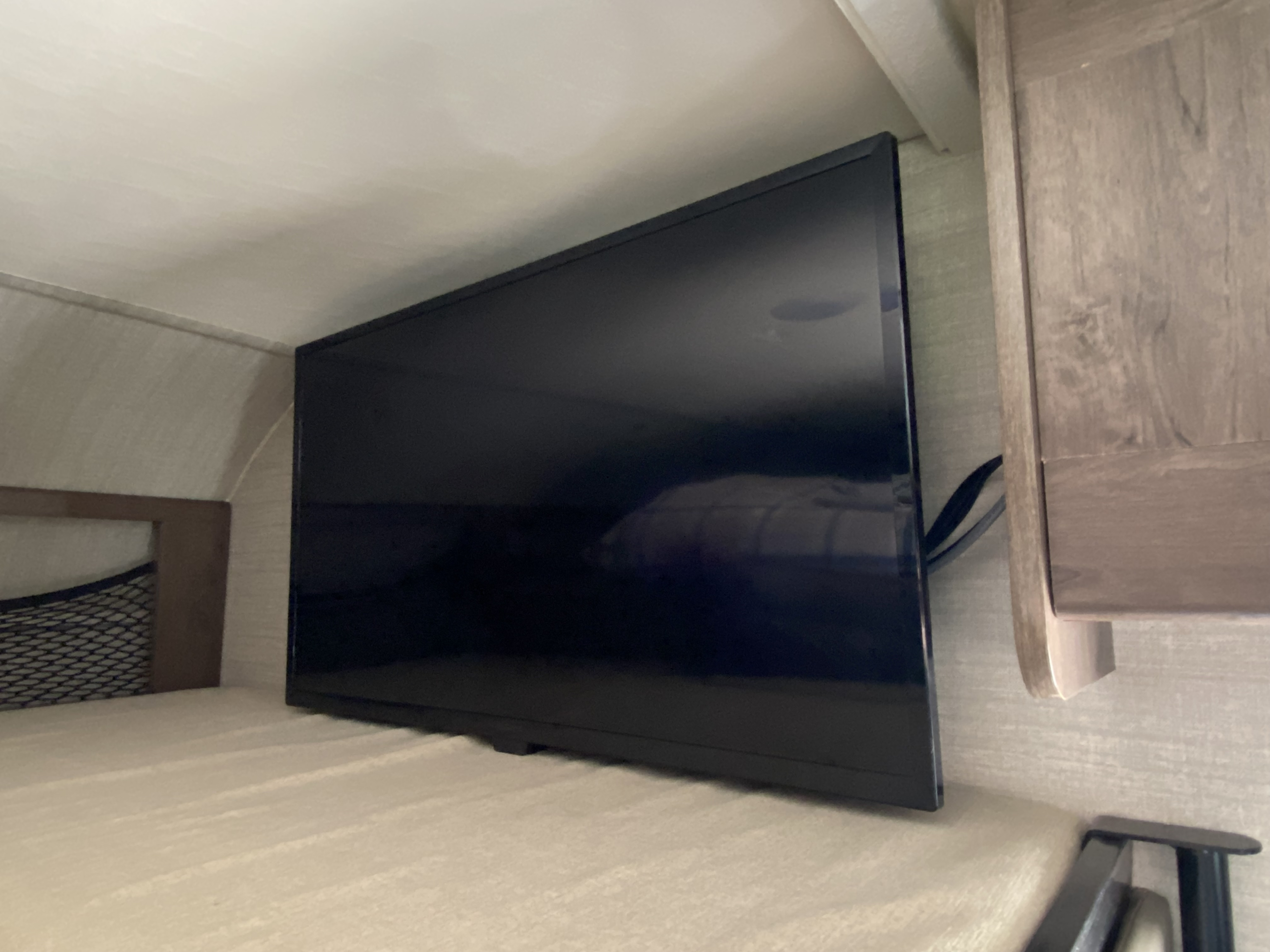Inside an RV rental: A flat-screen TV on a bunk bed, alongside a storage net and wood cabinetry. Perfect for travel comfort.. Jayco Melbourne 2020