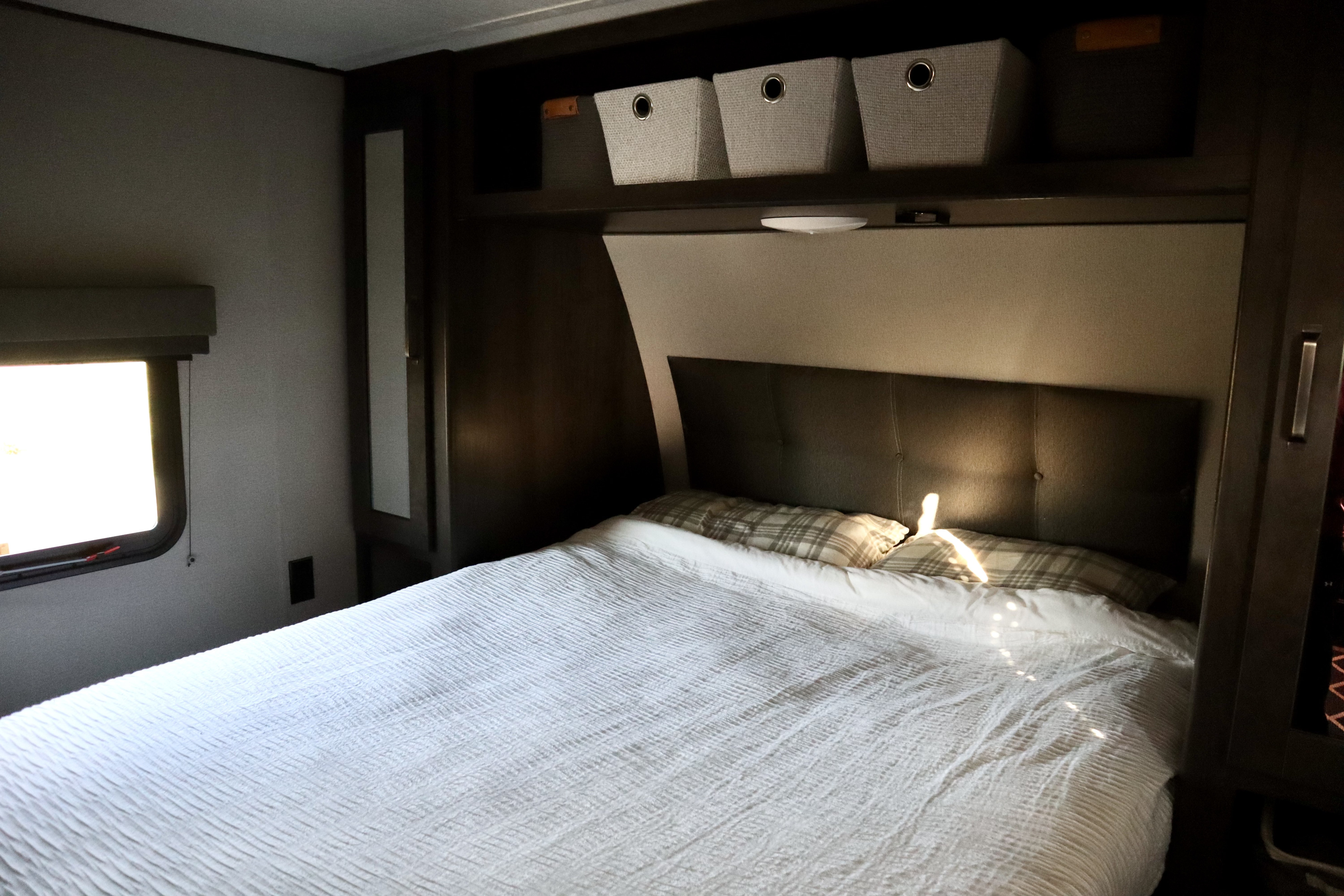 Inside this RV rental's bathroom: a bright, white compact shower with decorative trim and a toilet. Functional and clean.. Grand Design Transcend Xplor 2021