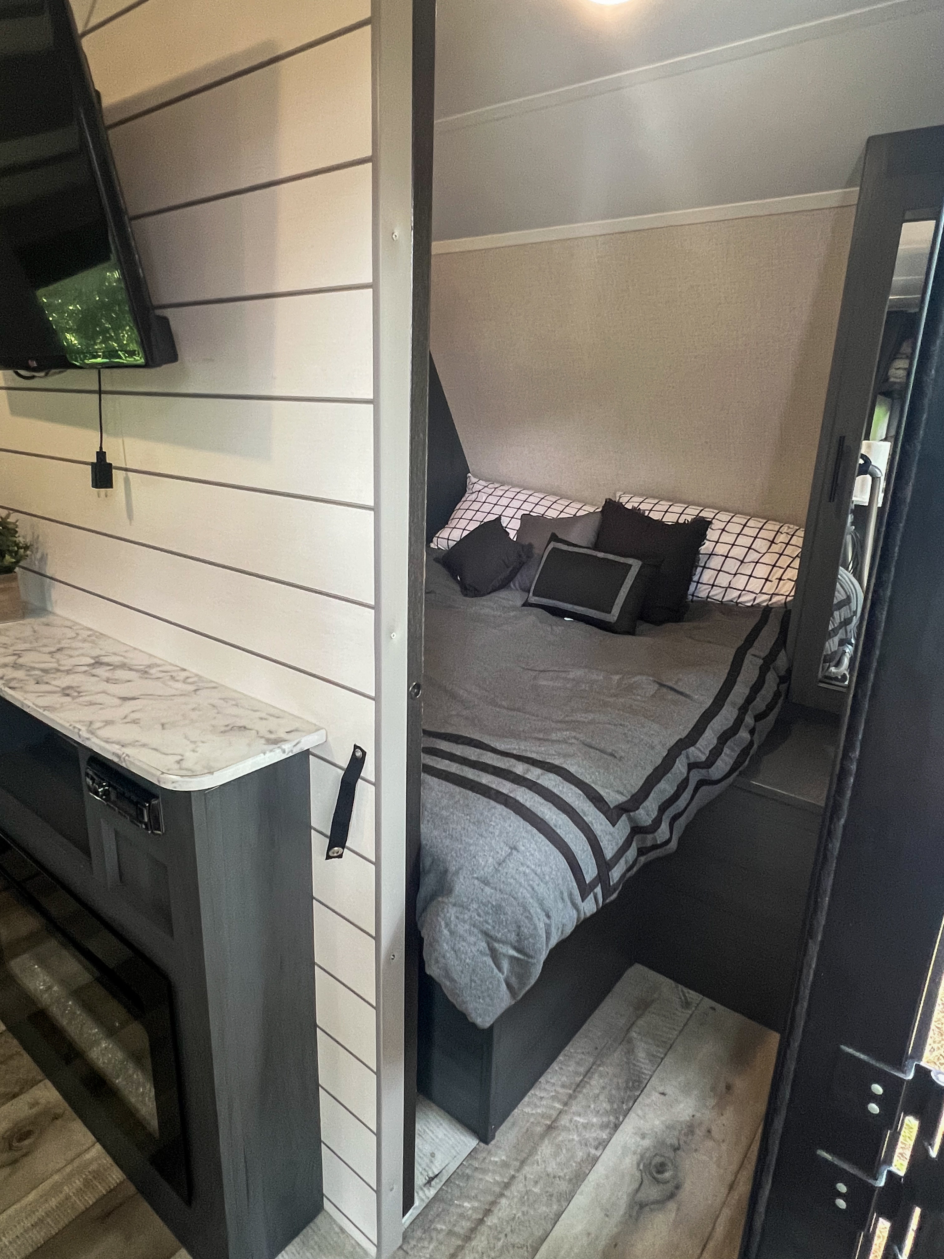 Explore this modern RV rental interior, showcasing a cozy bedroom, entertainment area, and stylish cabinetry.. Dutchmen Colorado 26BHC 2022