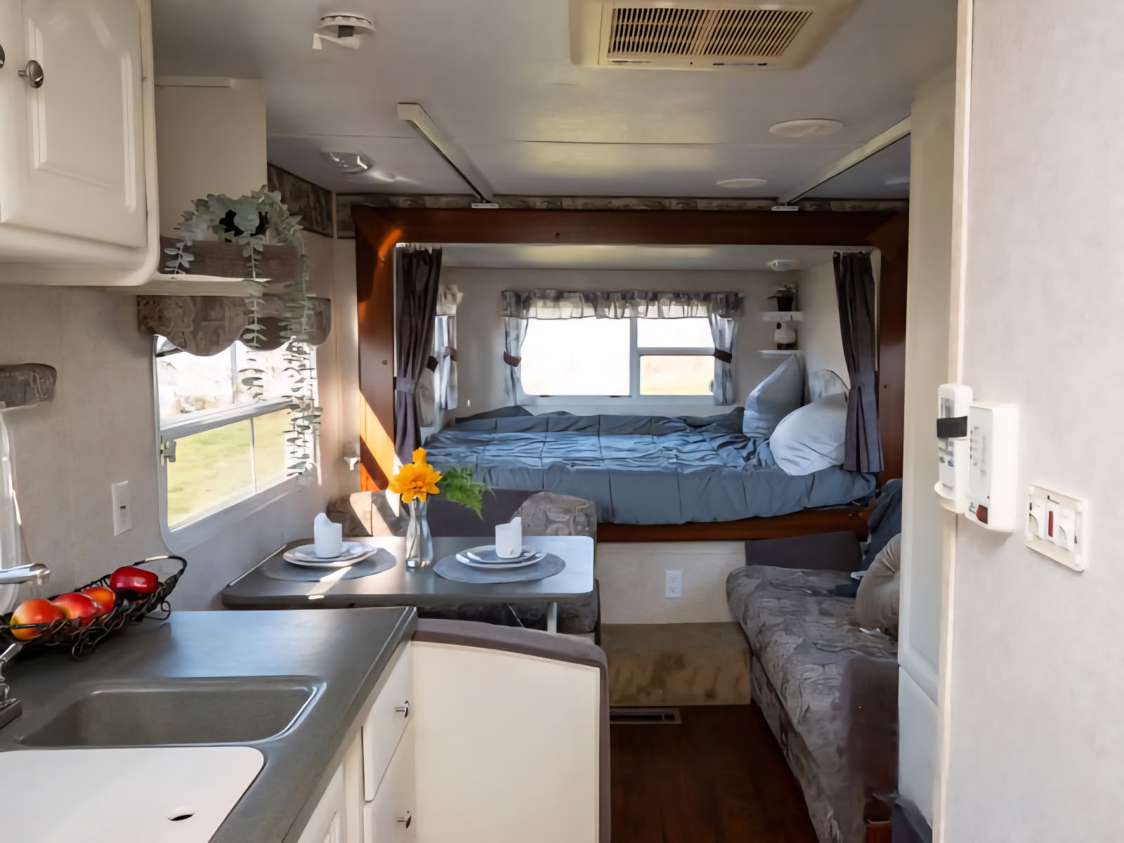 Cozy rv rental interior featuring a compact kitchen, dining area, and elevated bed. Ideal for mobile living.. Keystone RV Outback 21RS 2004