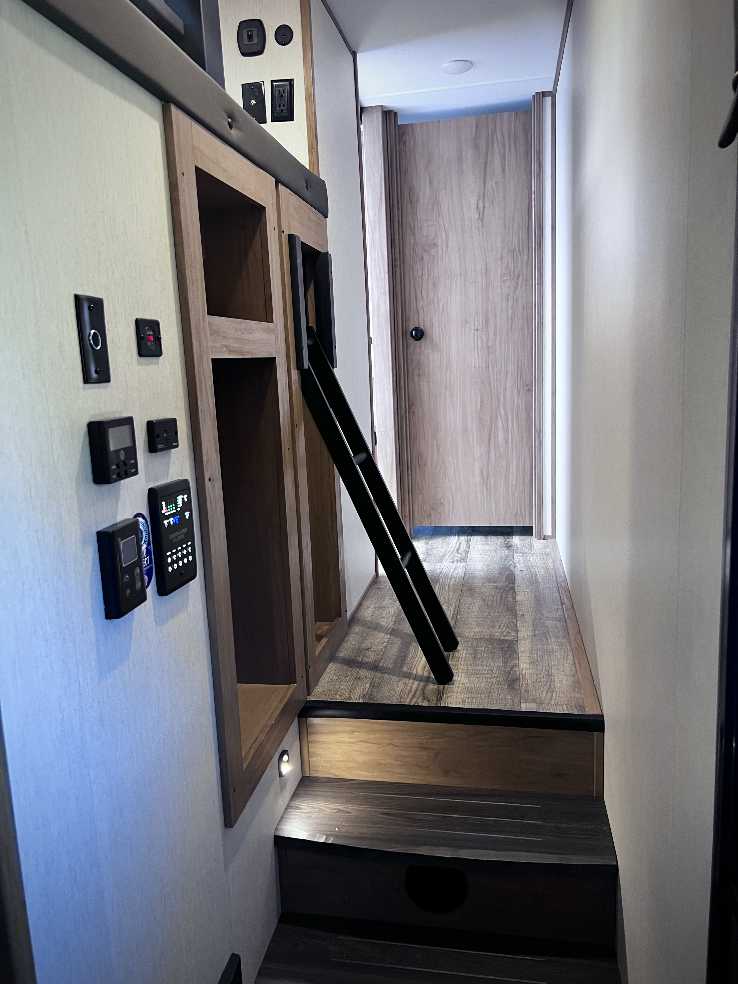 Inside an RV rental: Bunk bed with ladder, control panels, and steps to an upper sleeping area.. Forest River Cherokee Arctic Wolf 3660 Suite 2024